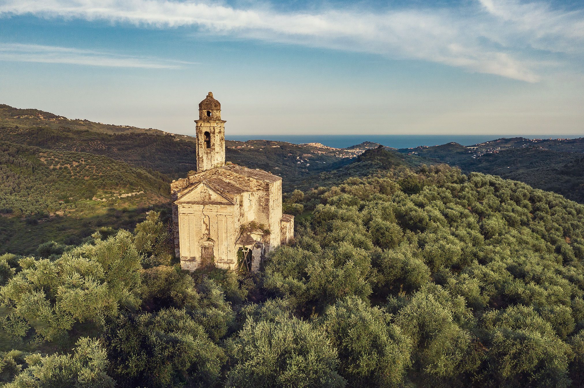 Kirche mit Glockenturm inmitten von Olivenhainen in den ligurischen Bergen, Italien
