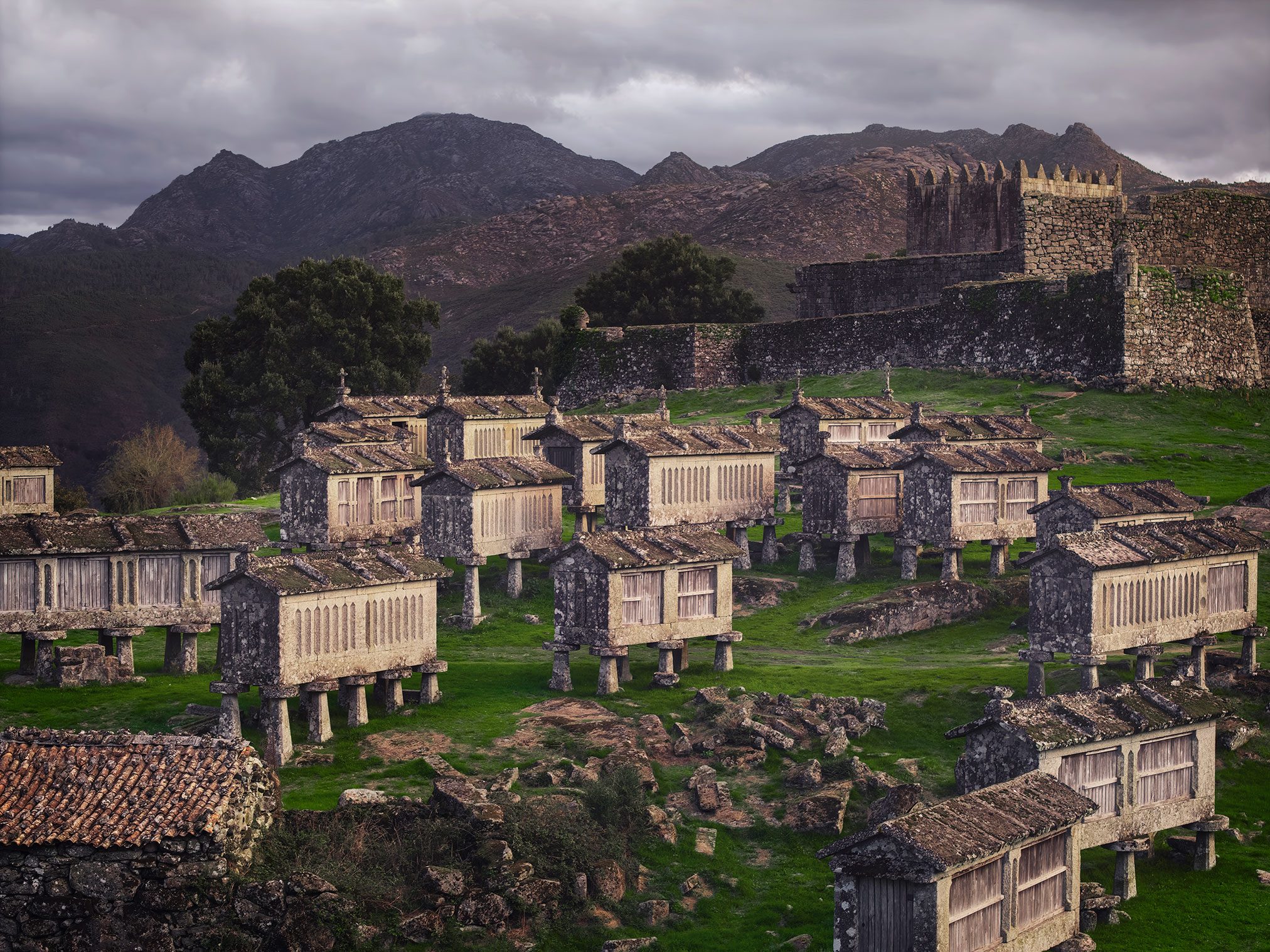 Stone granaries standing close together before a ruined castle in Portugal