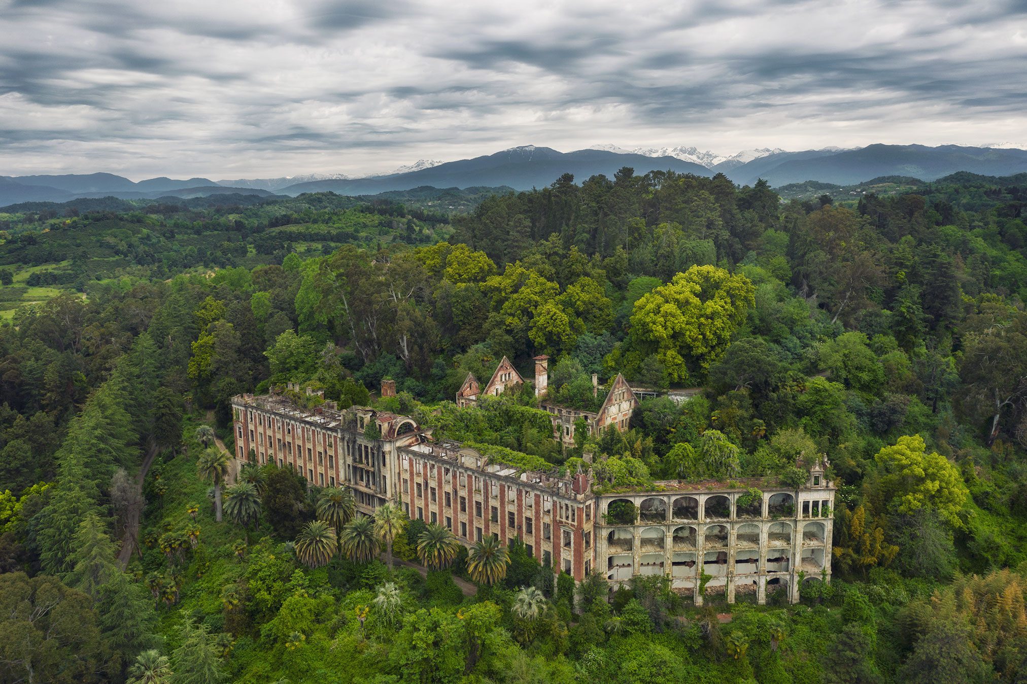 Elongated sanatorium with arcades in the forest before a mountain panorama, Abkhazia