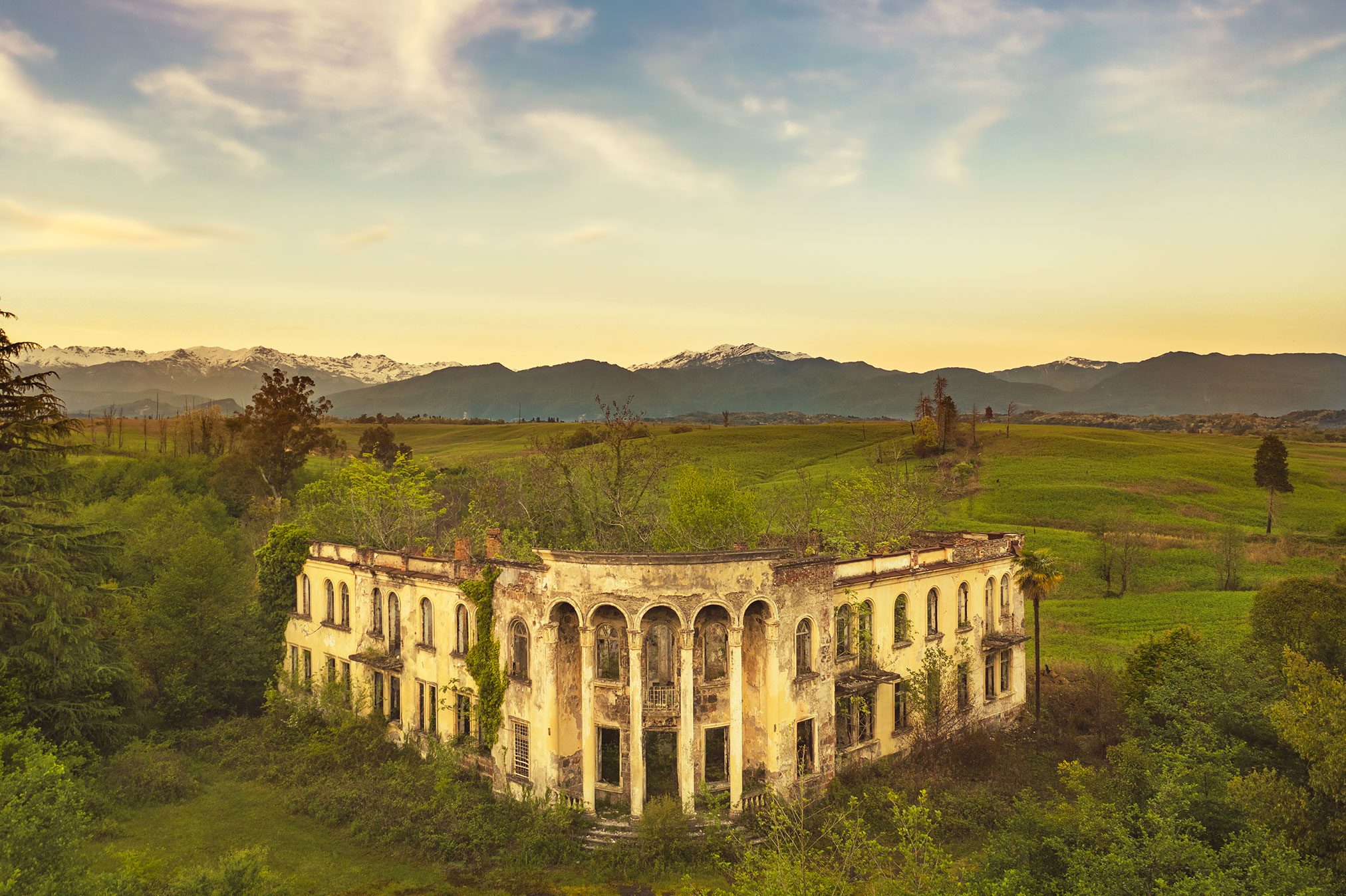 Ruin of a factory with arcades before snow capped mountains, Caucasus