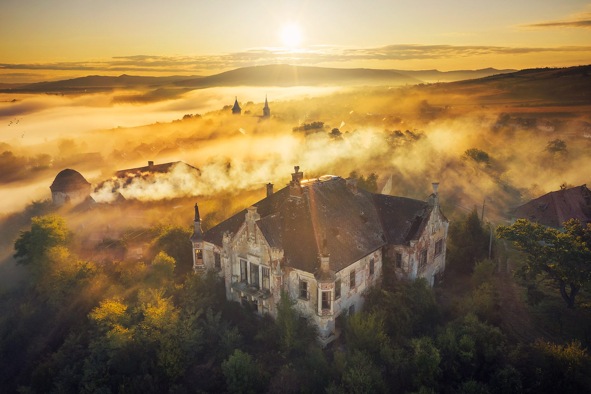 Manor house in morning mist with a round corner tower, Romania