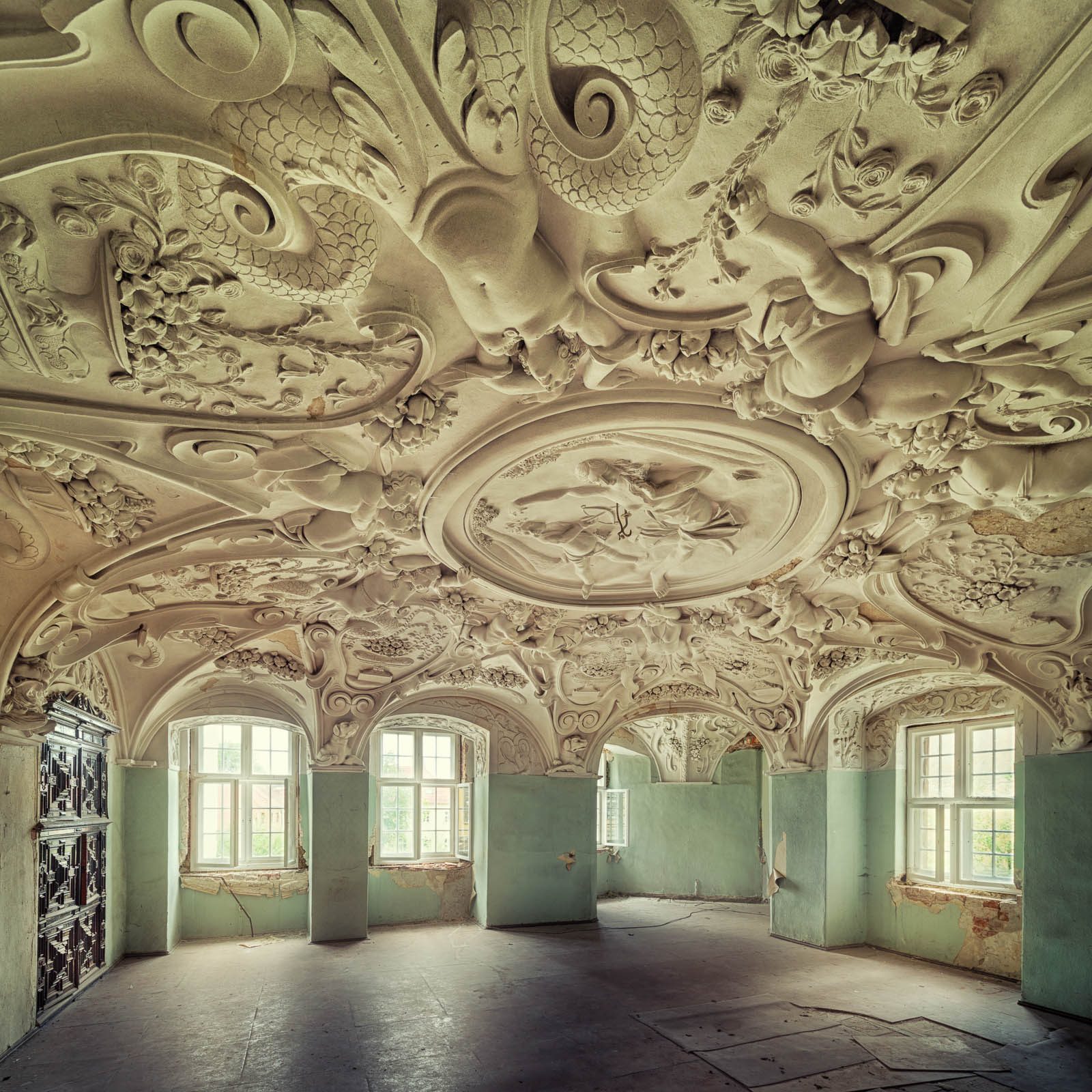Üppig stuckverzierte Decke über mintgrünen Wänden in einem Schloss in Deutschland