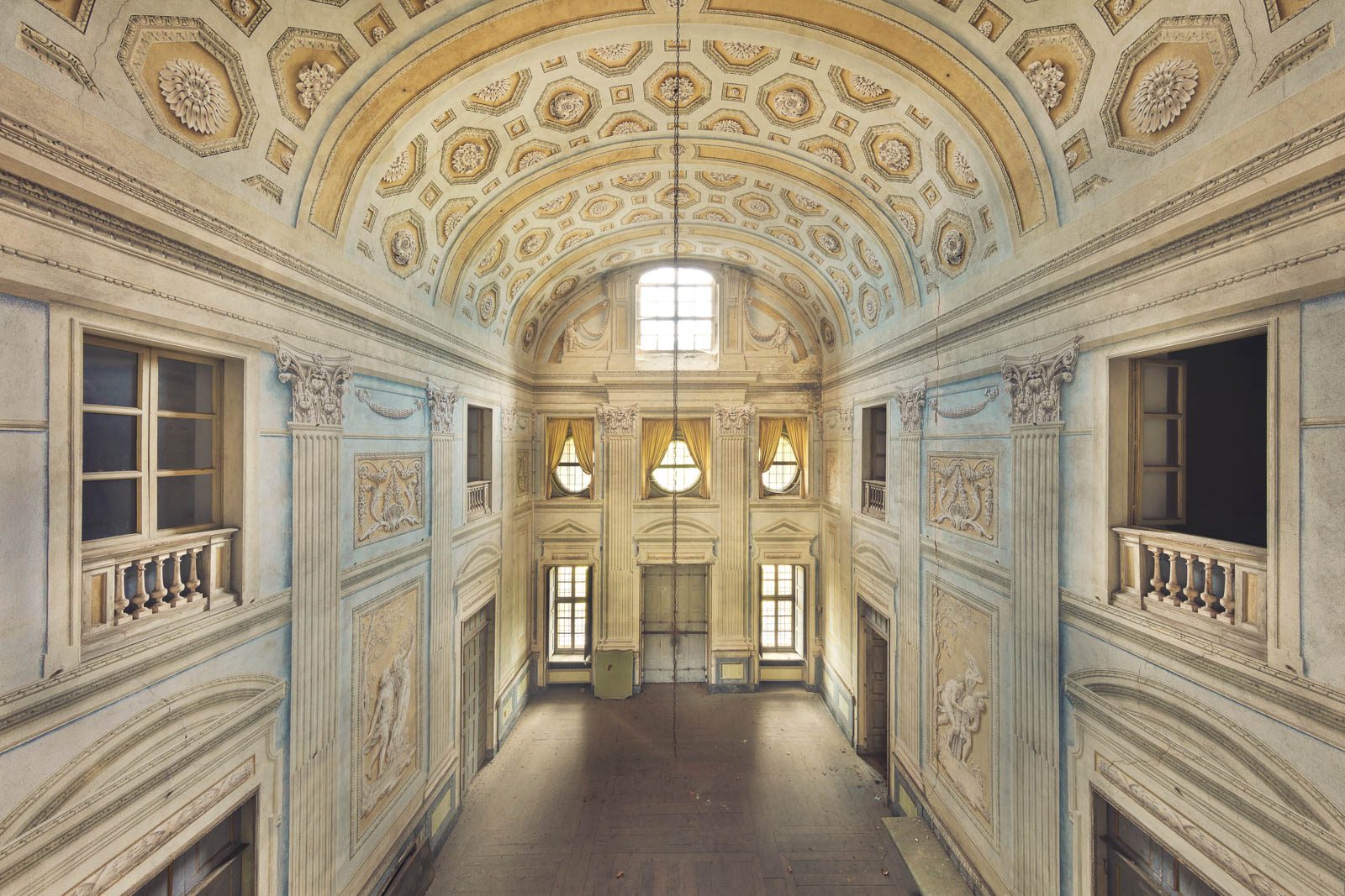 Symmetrical hall with a coffered ceiling and curtained windows in a villa in Piedmont, Italy