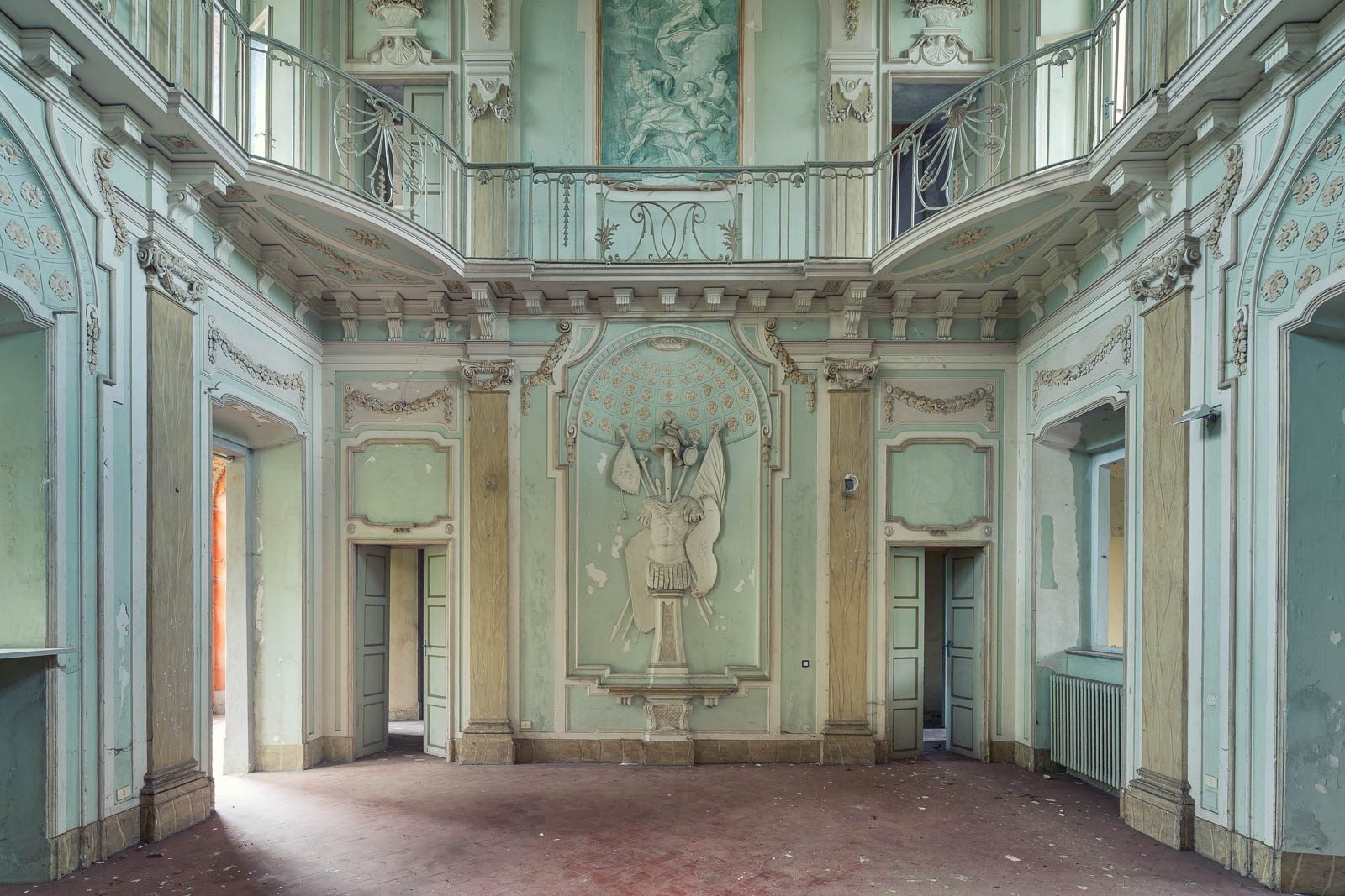 Mint-green hall with a stucco relief and an upper gallery in a villa in Piedmont, Italy