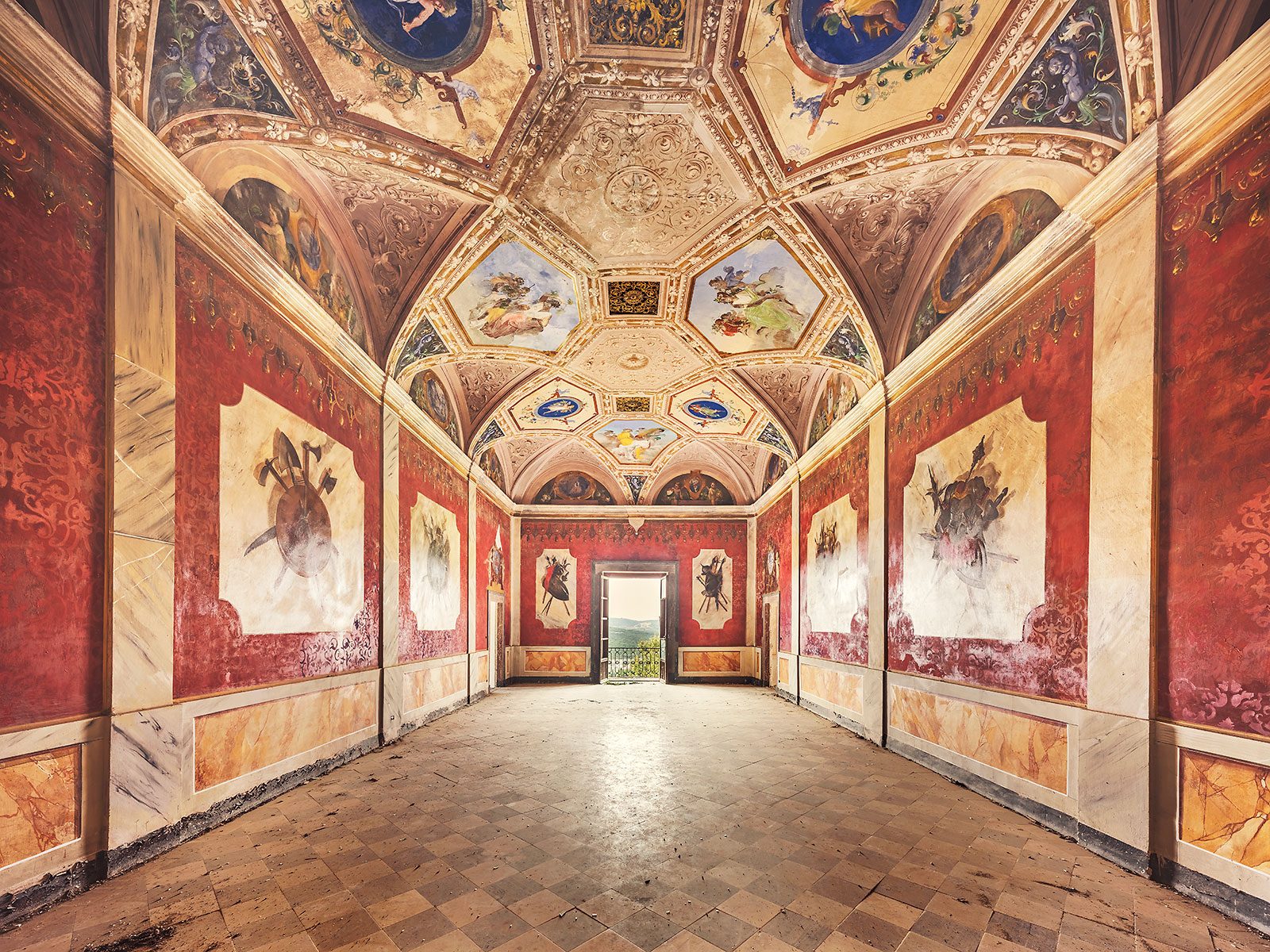 Fresco-decorated red hall with a coffered ceiling in an old monastery in Italy