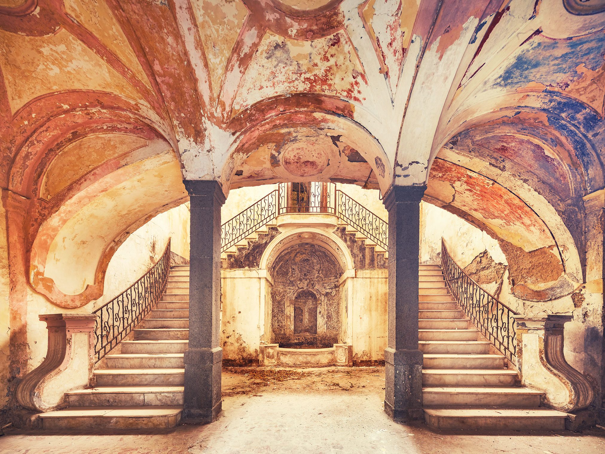 Symmetrical double staircase beneath a painted vault in a palazzo in Italy