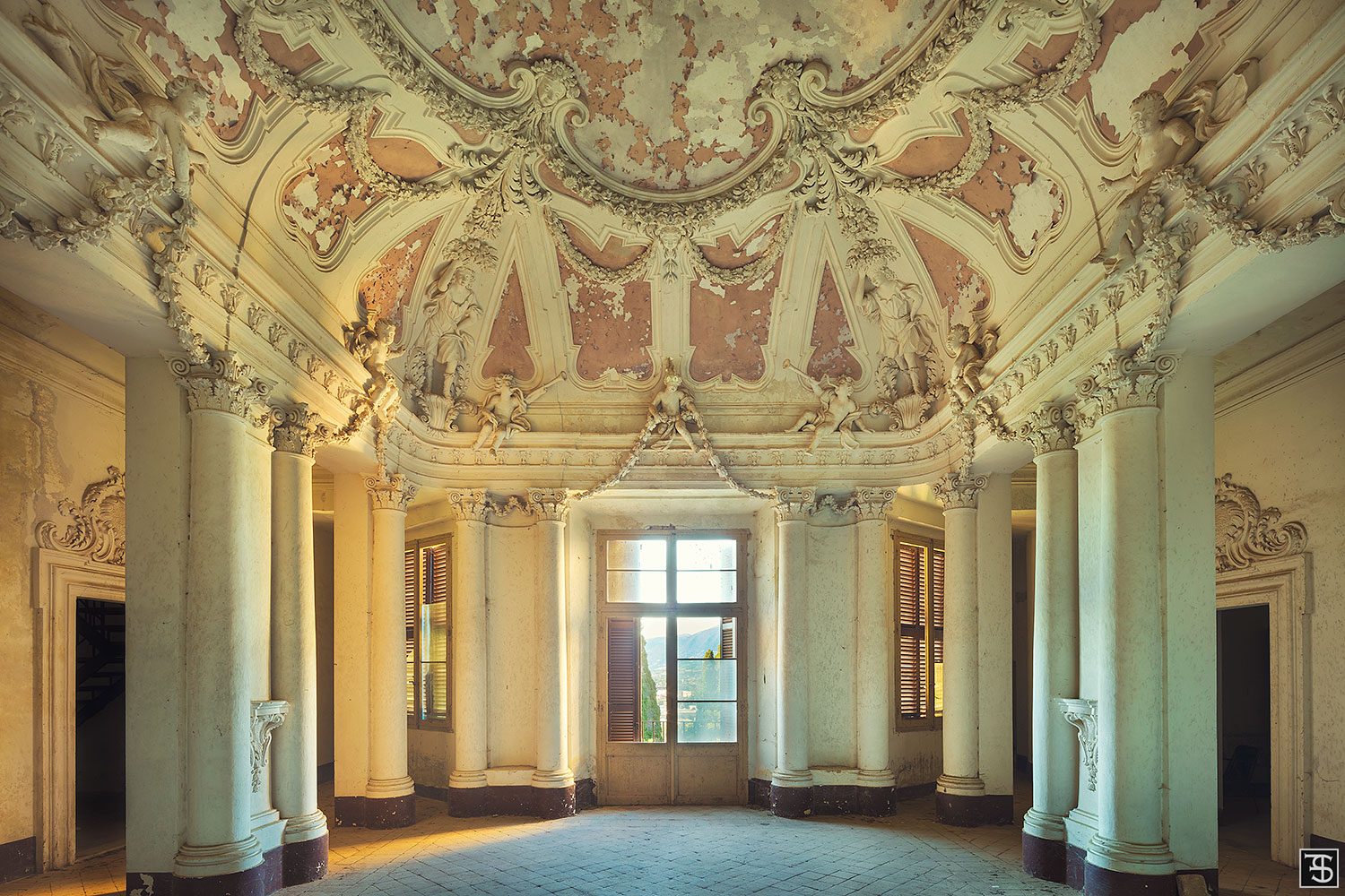 Stucco-decorated hall with putti and a terrace door on the upper floor of a villa in Umbria, Italy