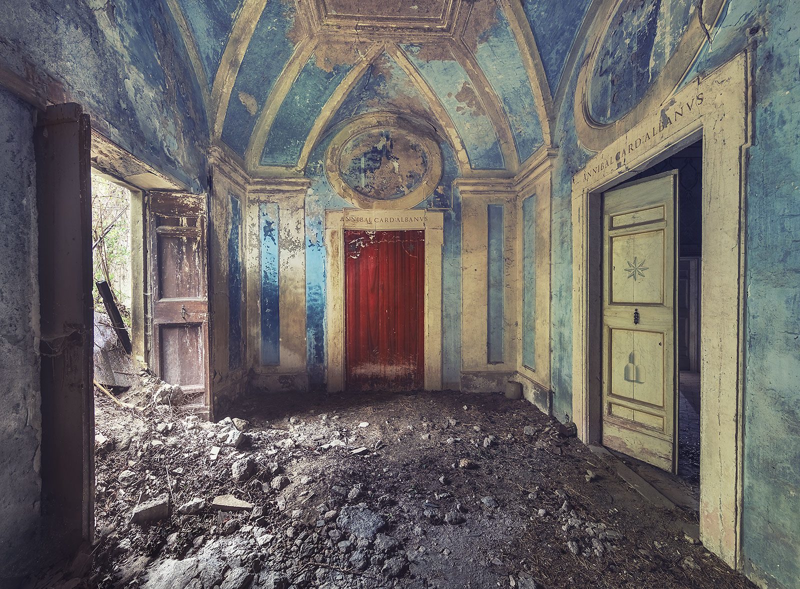 Blaues Vorzimmer mit Gewölbedecke und roter Tür in einem vergessenen Palazzo in Umbrien, Italien