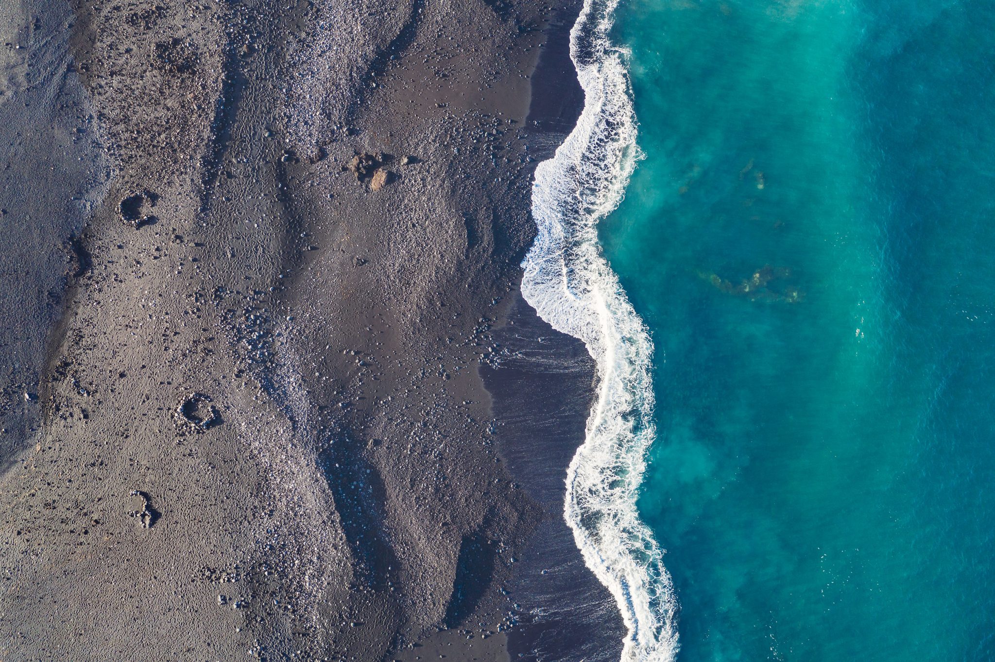 Luftaufnahme eines schwarzen Sandstrands mit Wellen auf Lanzarote, Spanien