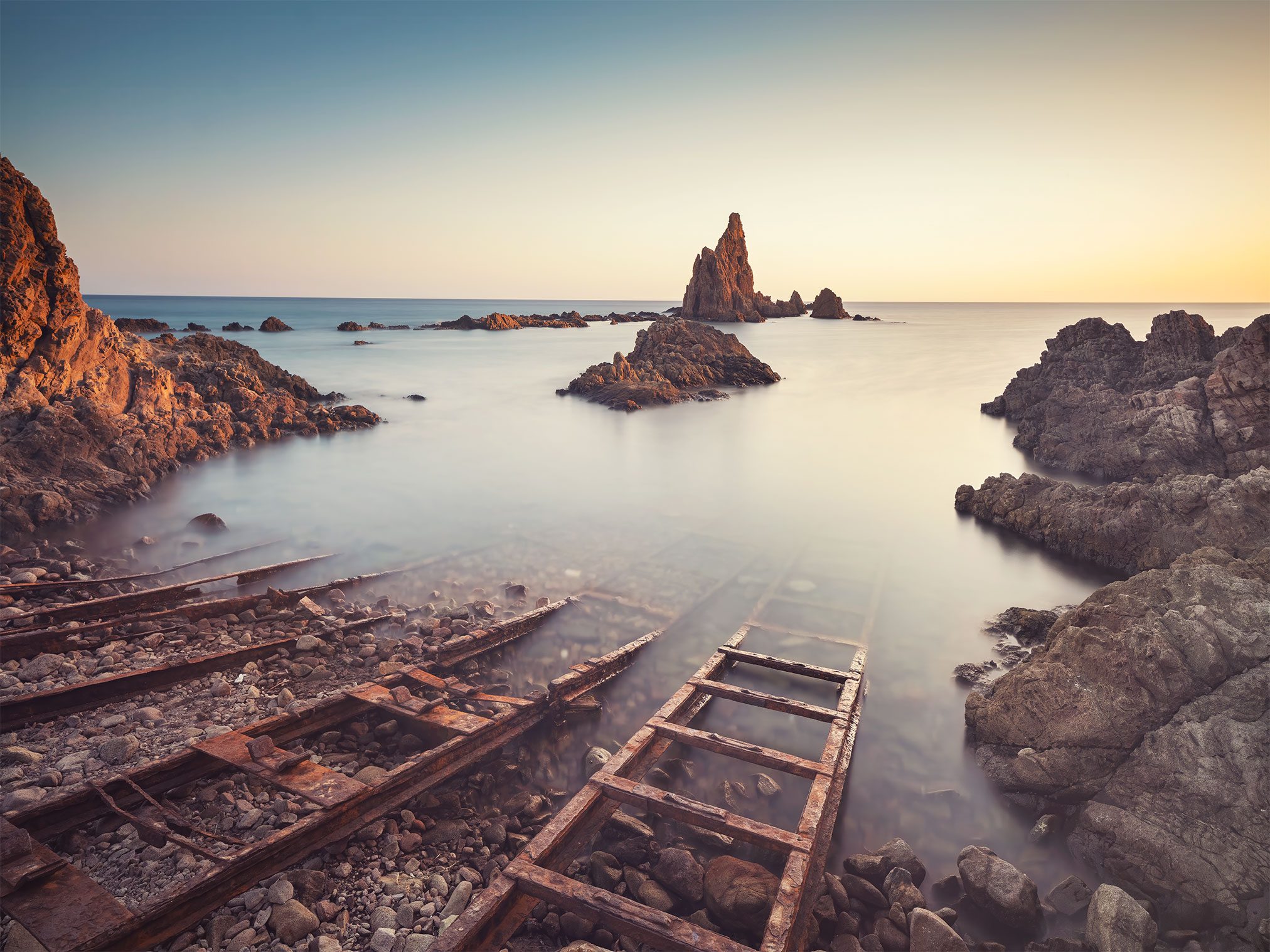 Rock spires in the sea beside old rail remains on the Spanish coast