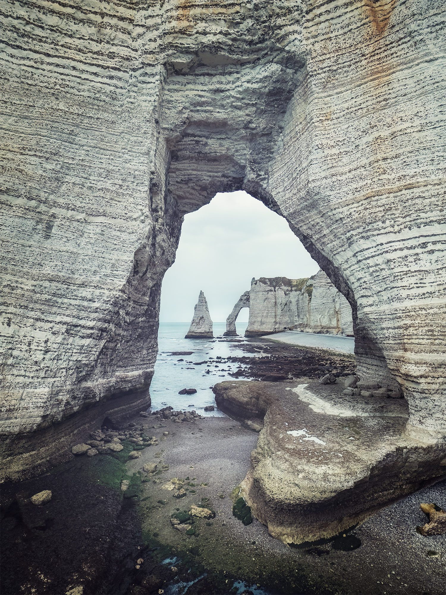 View through a chalk rock arch toward further cliffs at Étretat, France