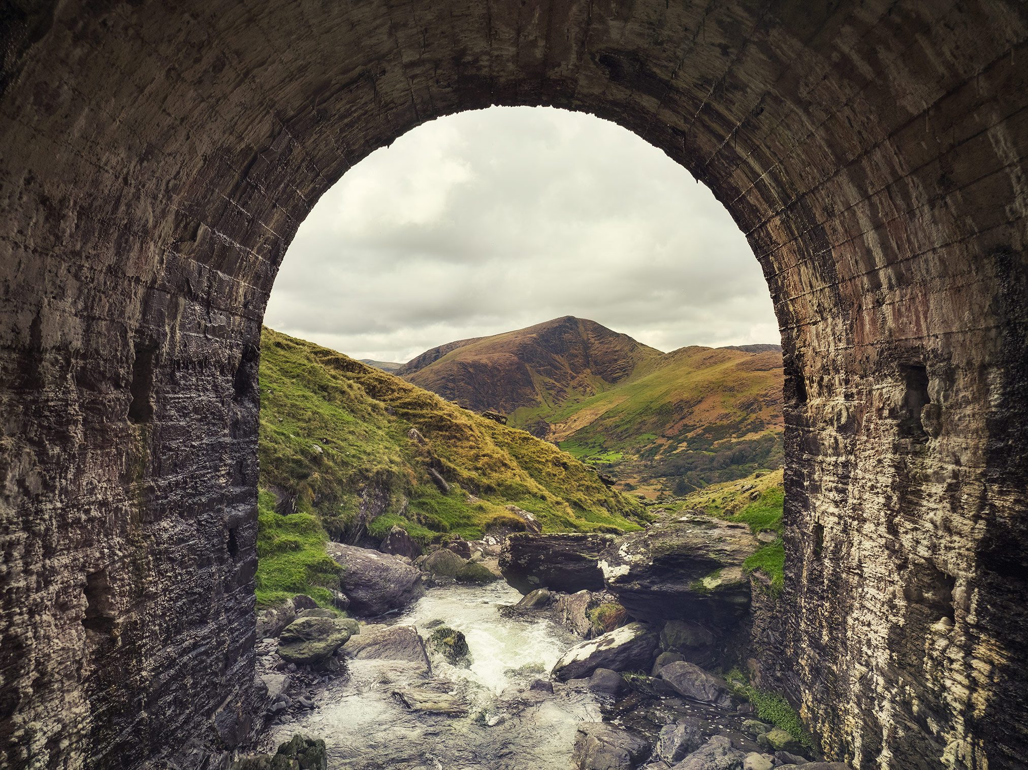 View through a stone tunnel toward a mountain valley at the Healy Pass, Ireland