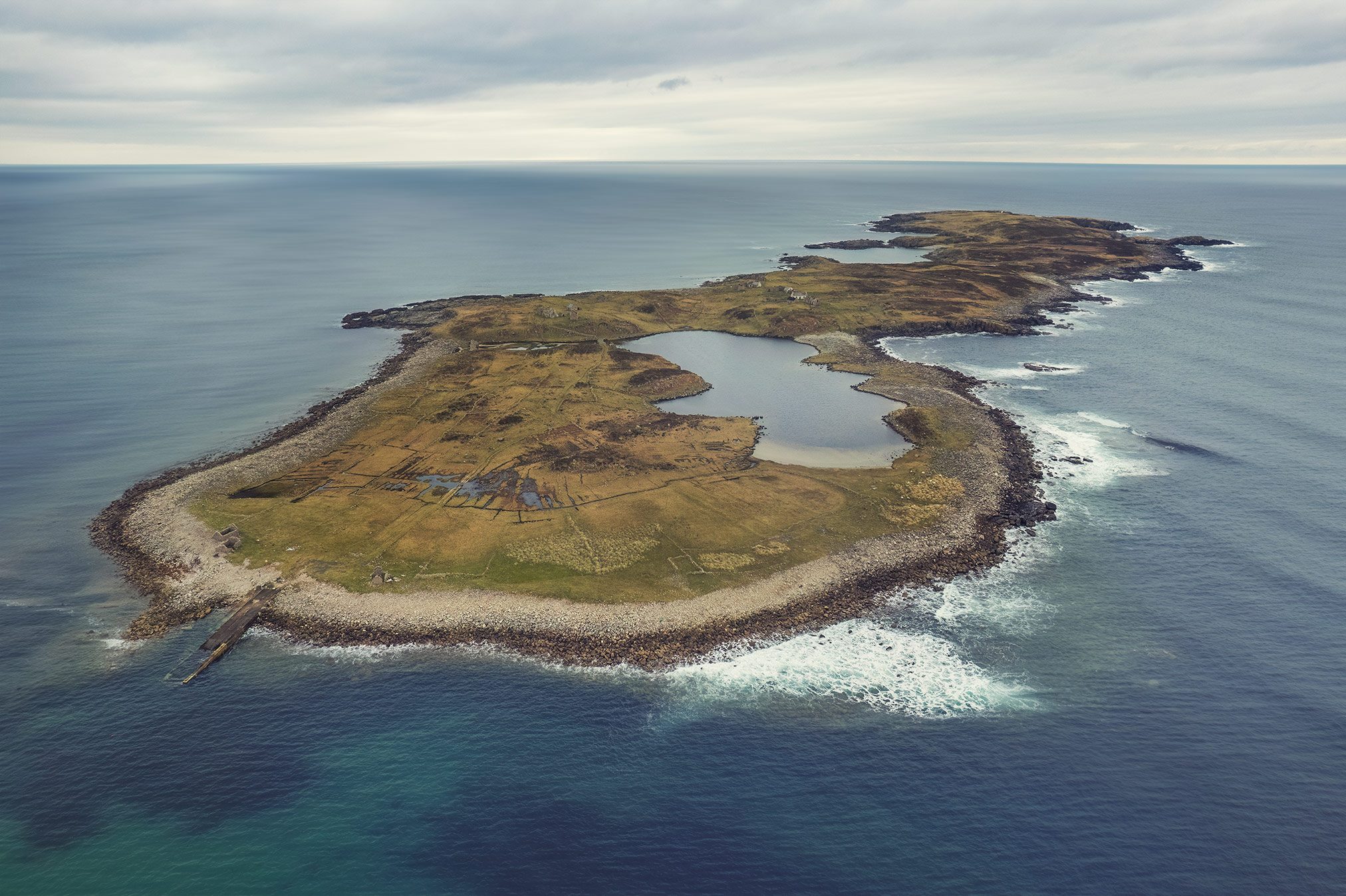Close aerial view of an island settlement with visible ruin remains off Ireland