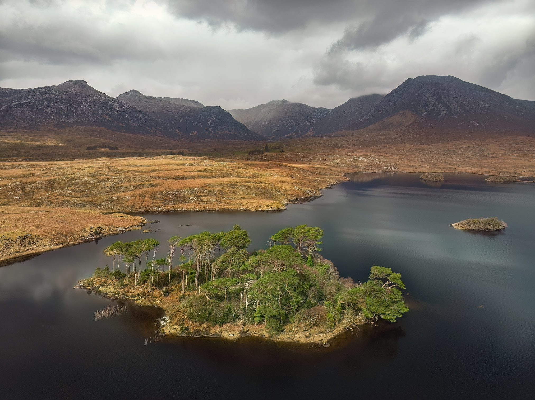 Bewaldete Insel in einem See vor Berglandschaft im Connemara Nationalpark, Irland