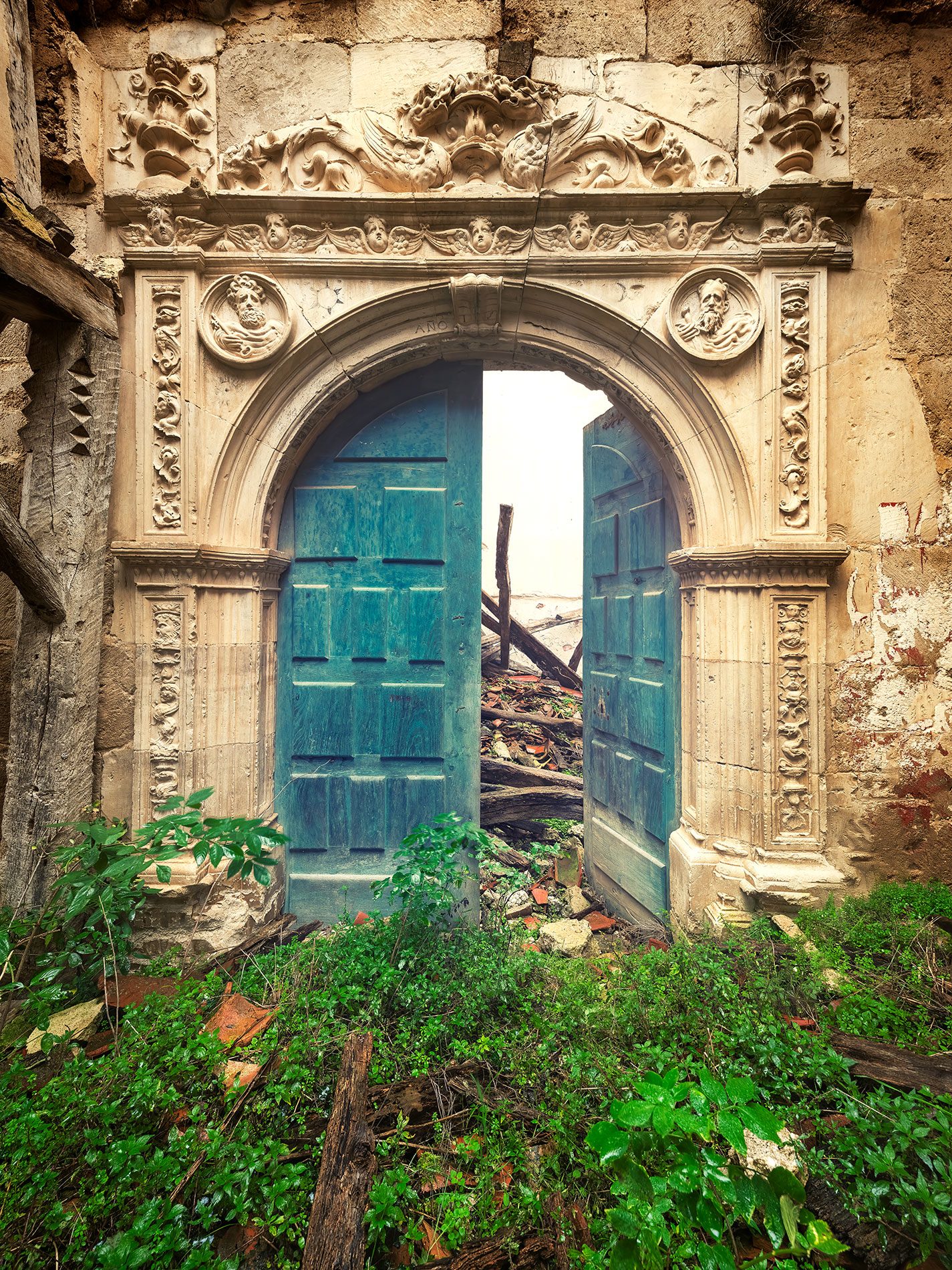 Turquoise door in a richly carved stone portal of a church in Spain