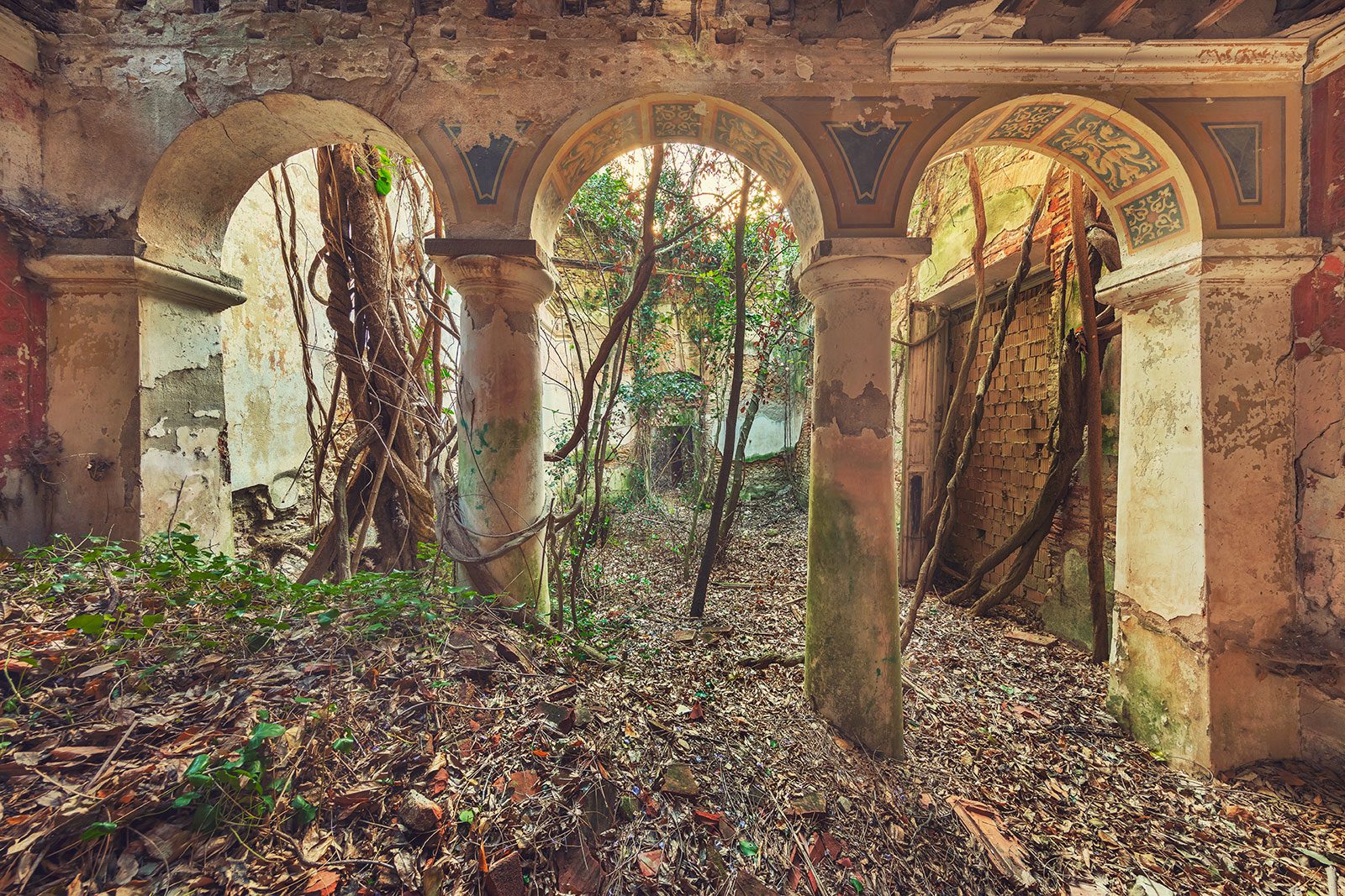 Three round arches with painted decoration in a ruined palazzo in Italy