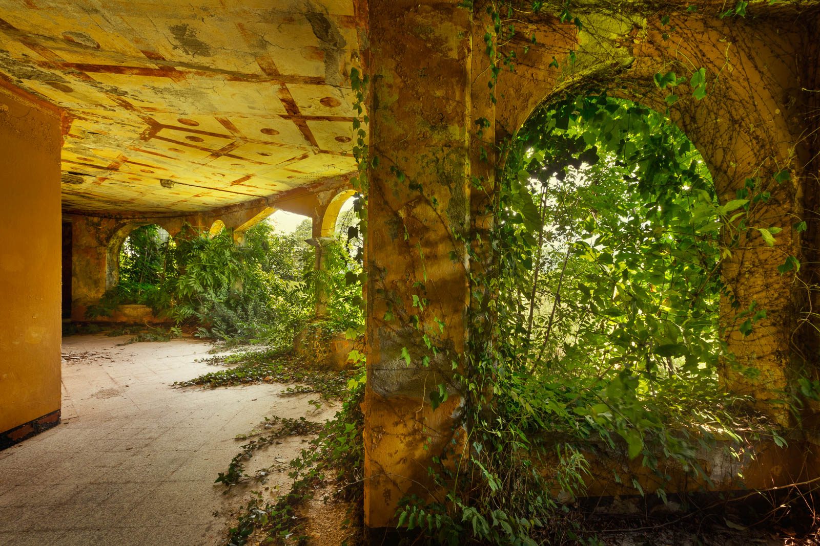 Ivy-covered arched corridor of an abandoned holiday camp on Lake Maggiore, Italy