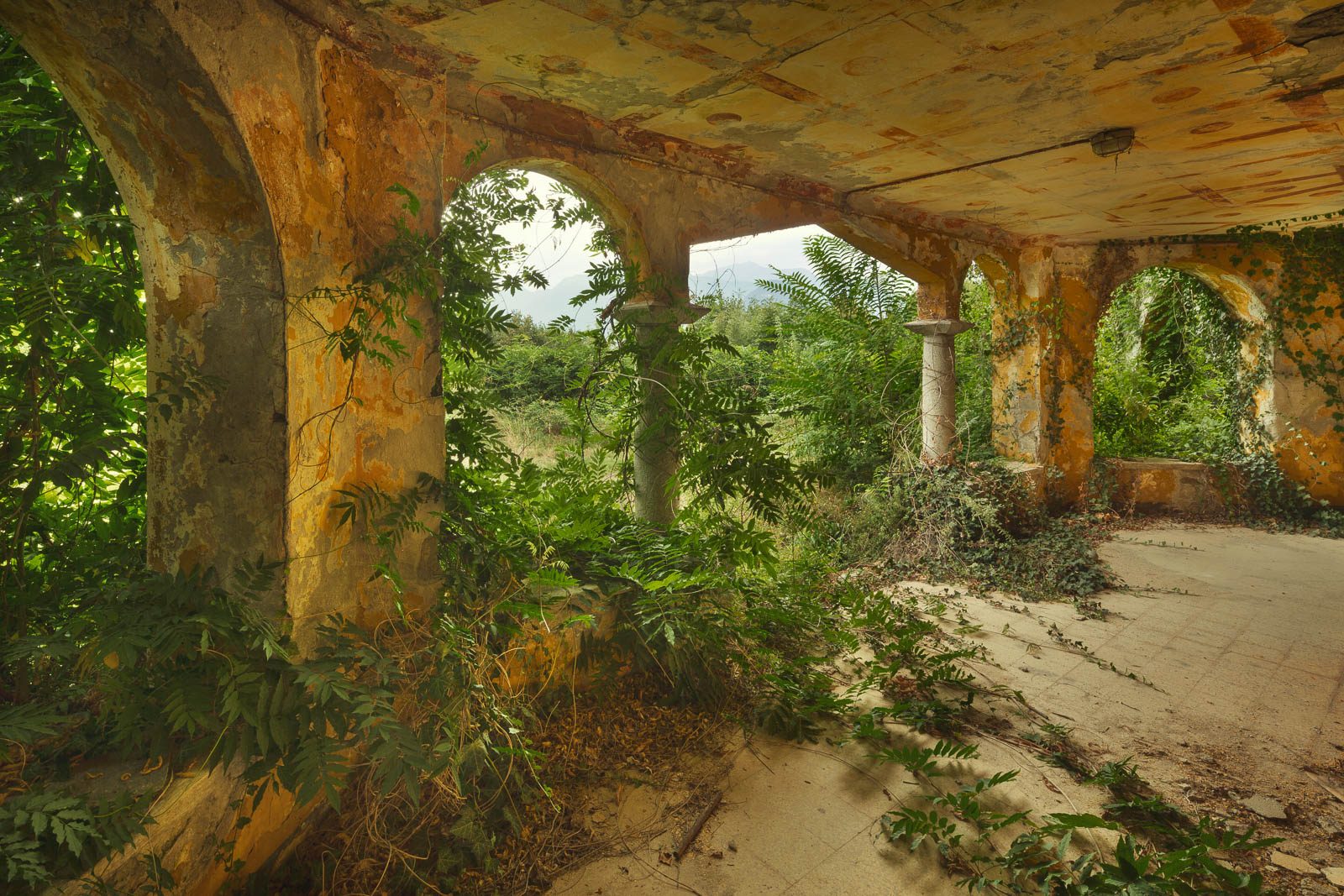 Arched corridor with a mountain view in an abandoned holiday camp on Lake Maggiore, Italy