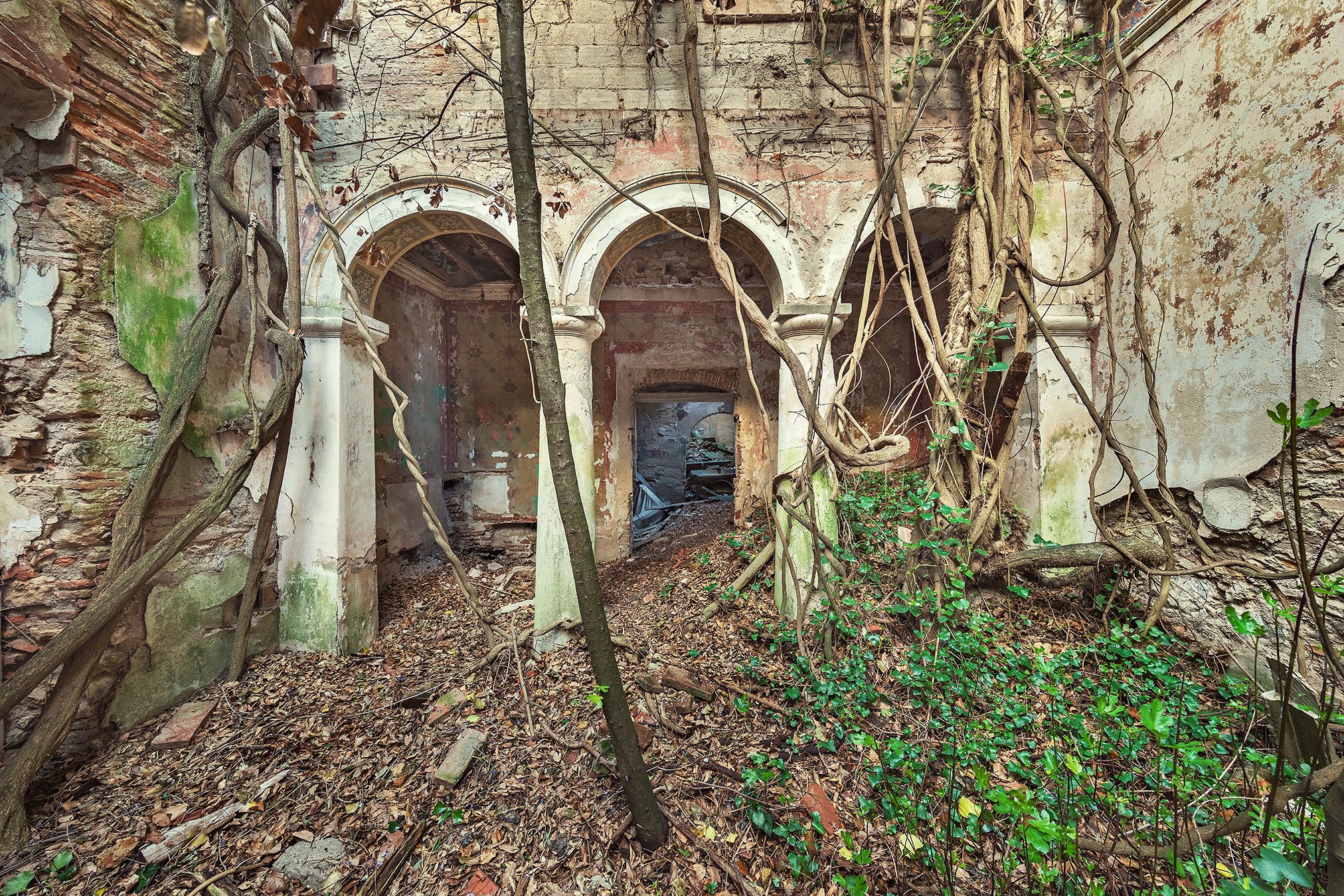 Arched corridor with faded frescoes in a ruined villa in Tuscany, Italy