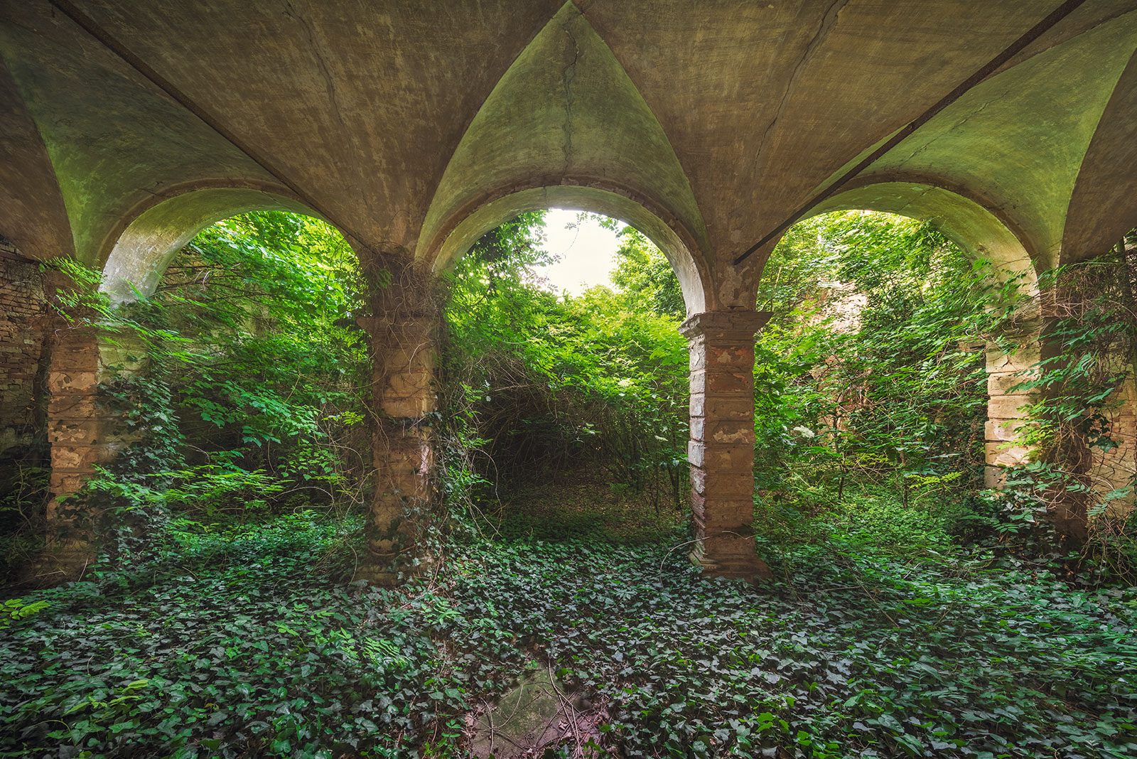 Gewölbte Arkade mit Blick ins Grüne in einem Palazzo in der Lombardei, Italien
