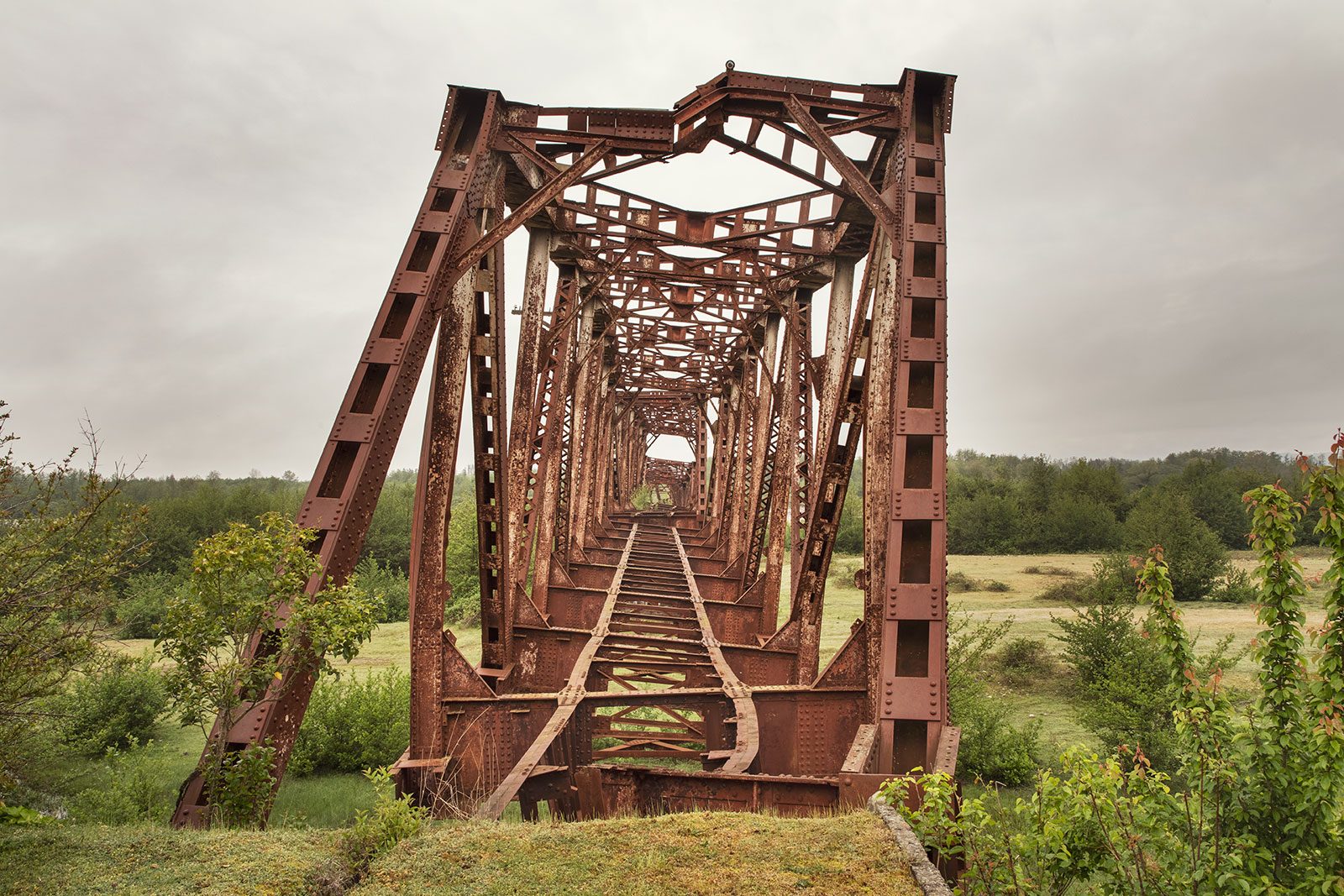 Rusting truss bridge spanning a grassy field on the border with Abkhazia, Georgia