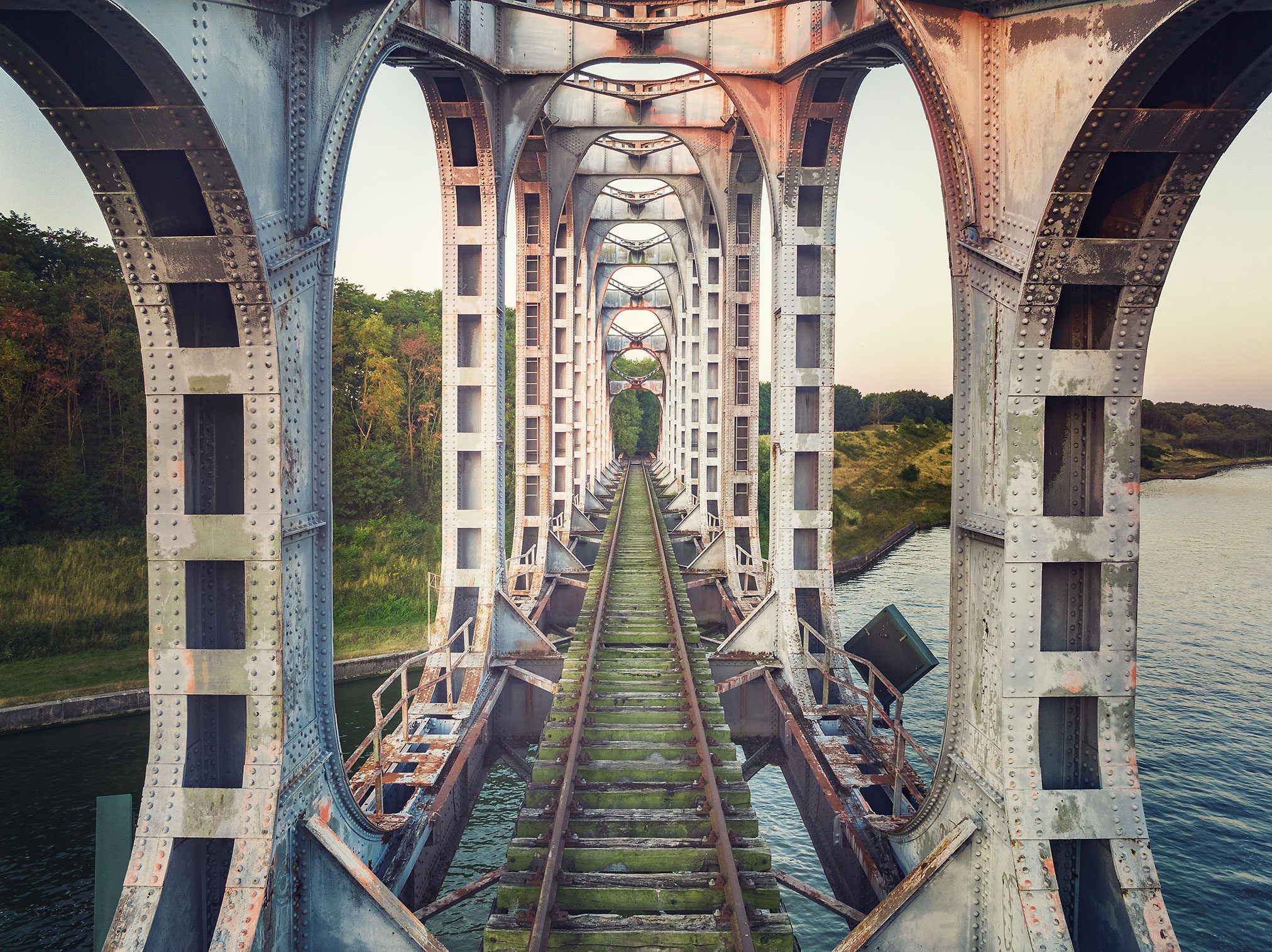 Stillgelegte Eisenbahnbrücke mit rostigen Stahlbögen über einem Wasserlauf in den Niederlanden