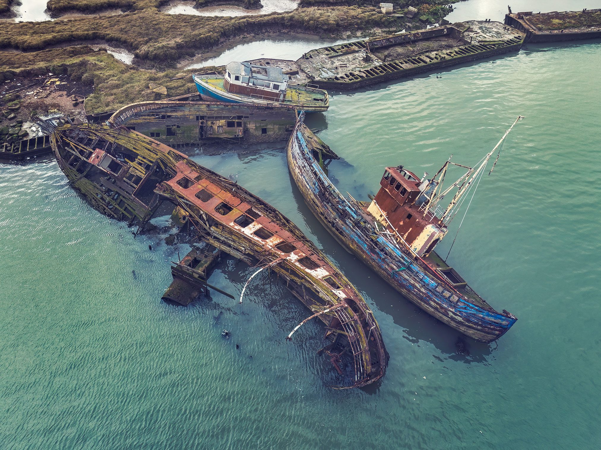Sunken ship wrecks in turquoise coastal water in England, aerial view