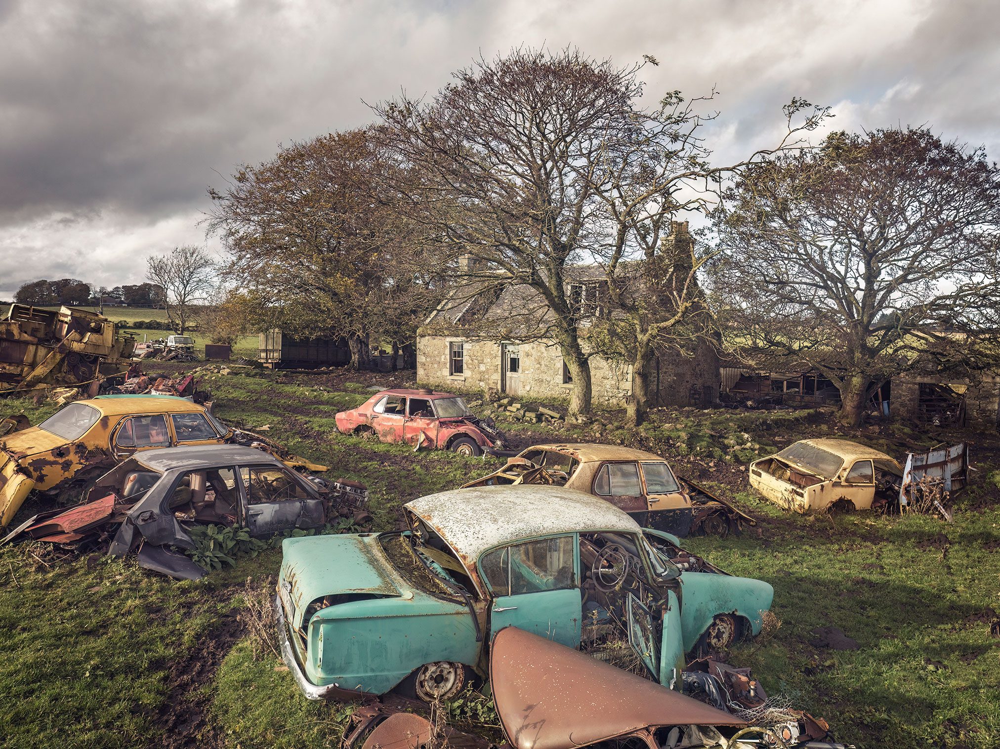 Car graveyard in front of an abandoned stone farmhouse in the Scottish Highlands