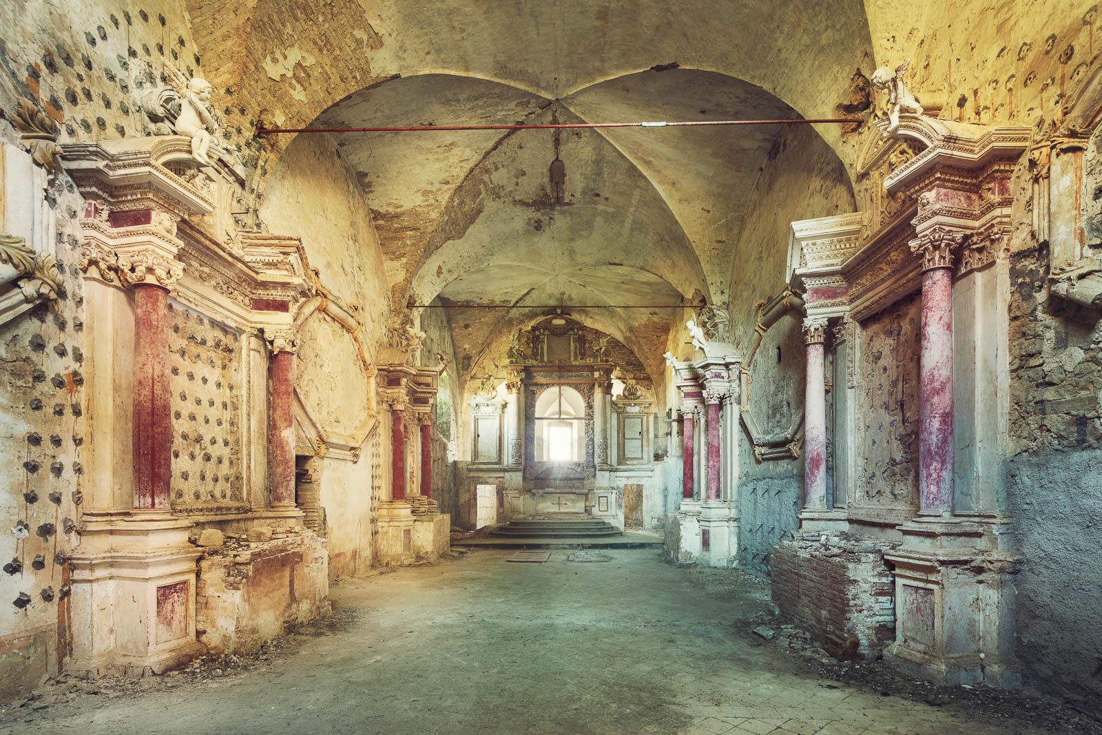 Groin vaulted corridor with reddish columns in a monastery in Italy