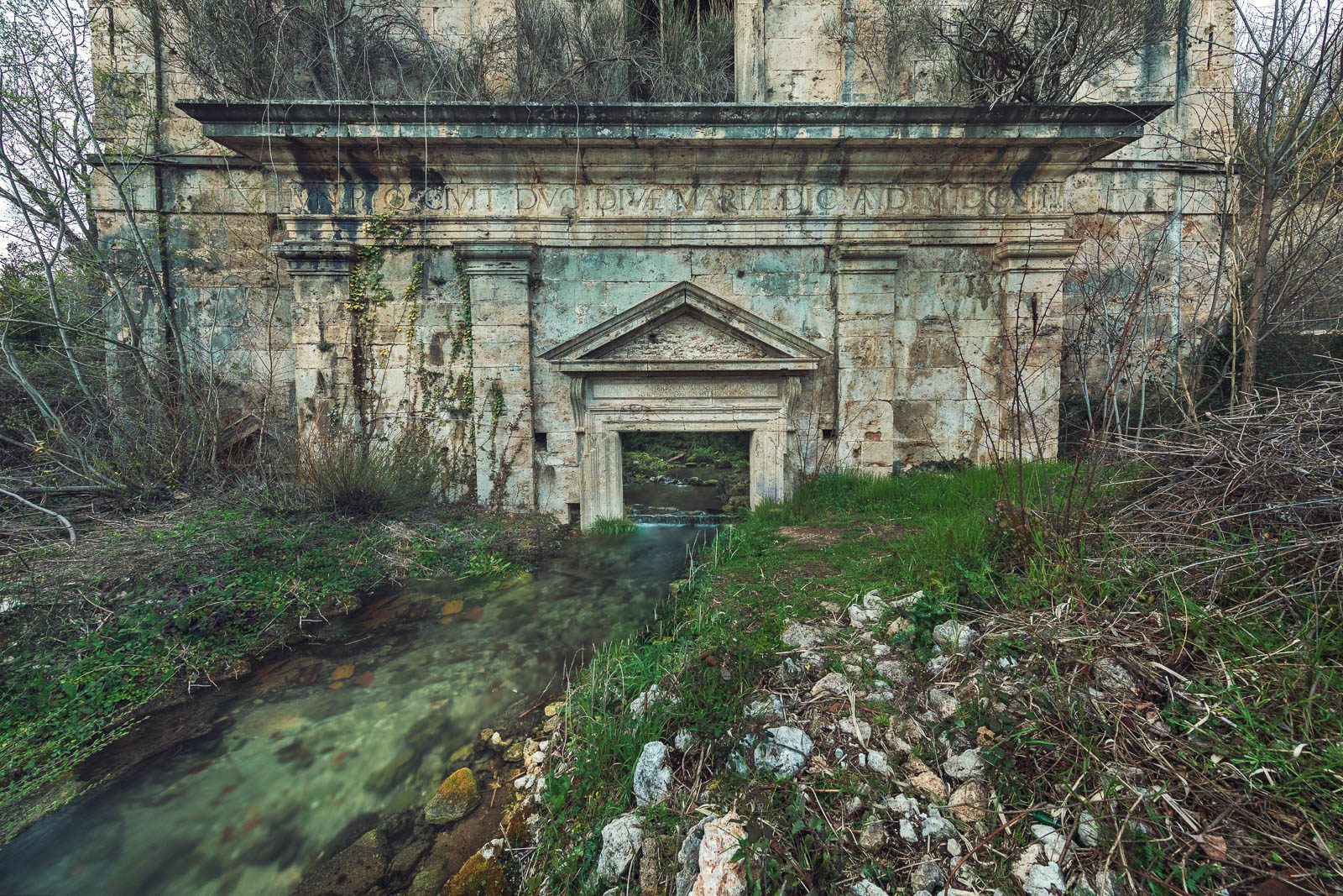 Stone gate facade over a watercourse in Italy
