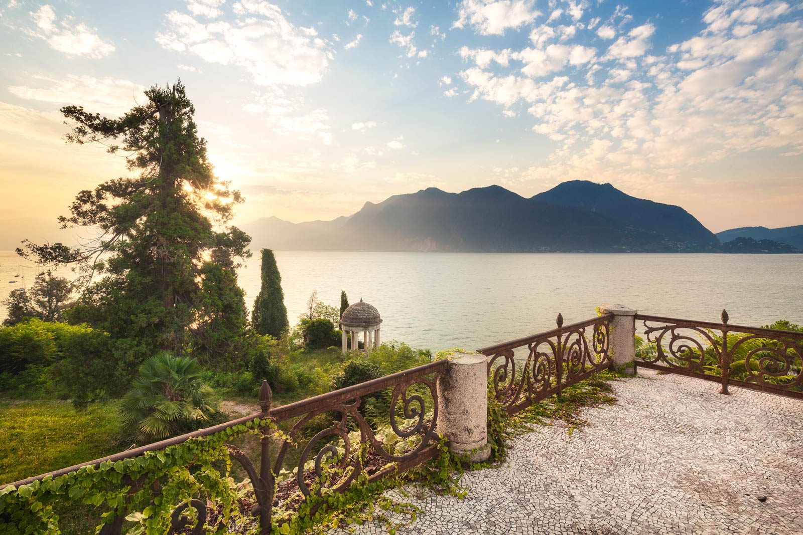 Terrace with a wrought iron railing and a pavilion on a lake, Italy