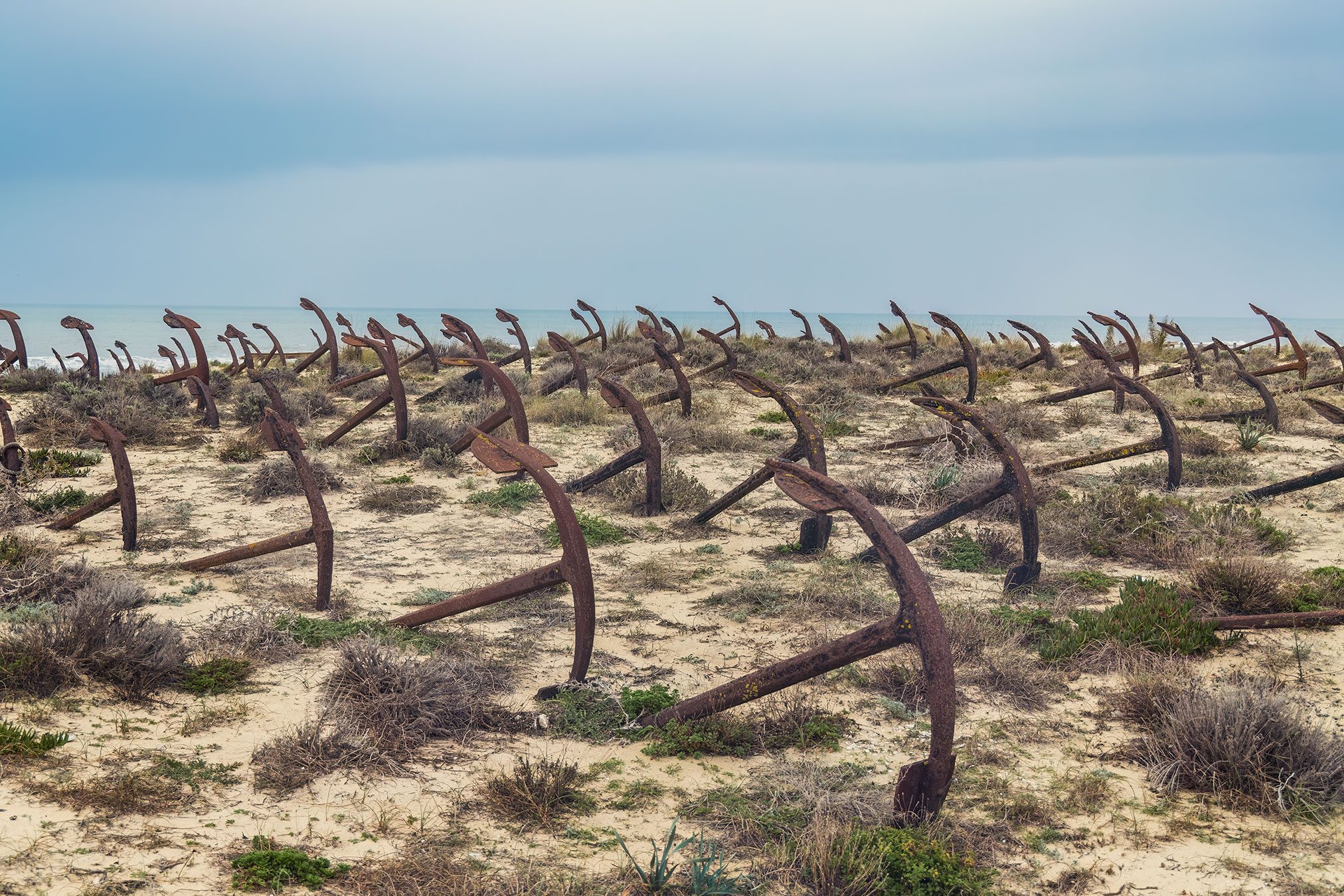 Rows of rusted ship anchors in the dunes on the Portuguese coast