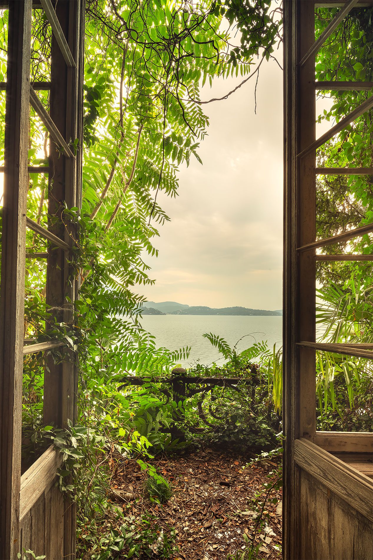 Open door in a garden wall with a lake view in Italy