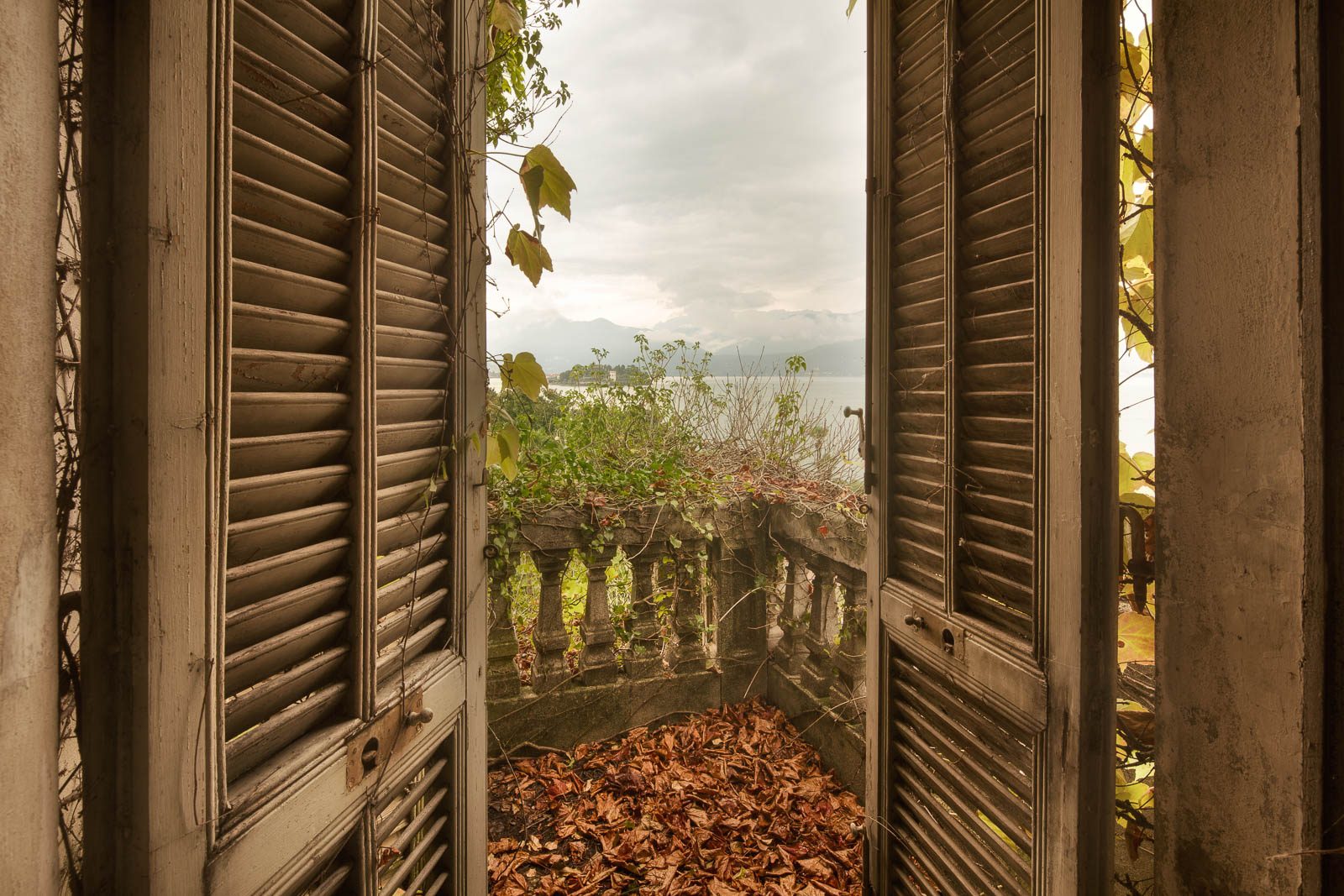 Open shutter revealing a balustrade and a lake beyond, Italy