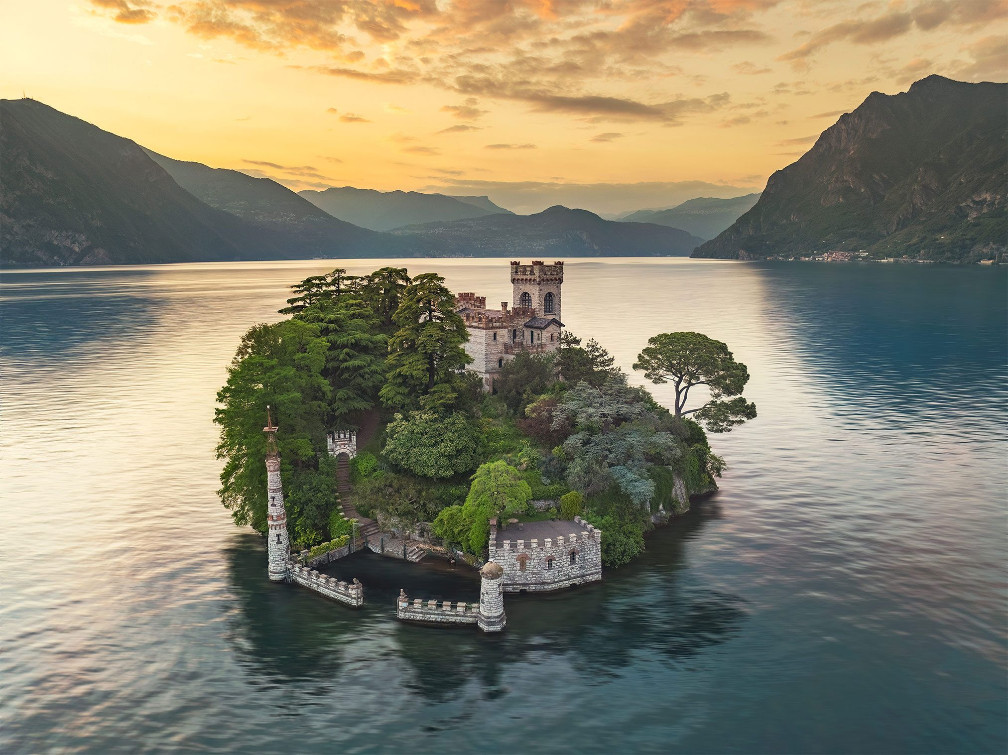 Tree covered castle island with a tower on a lake in Italy