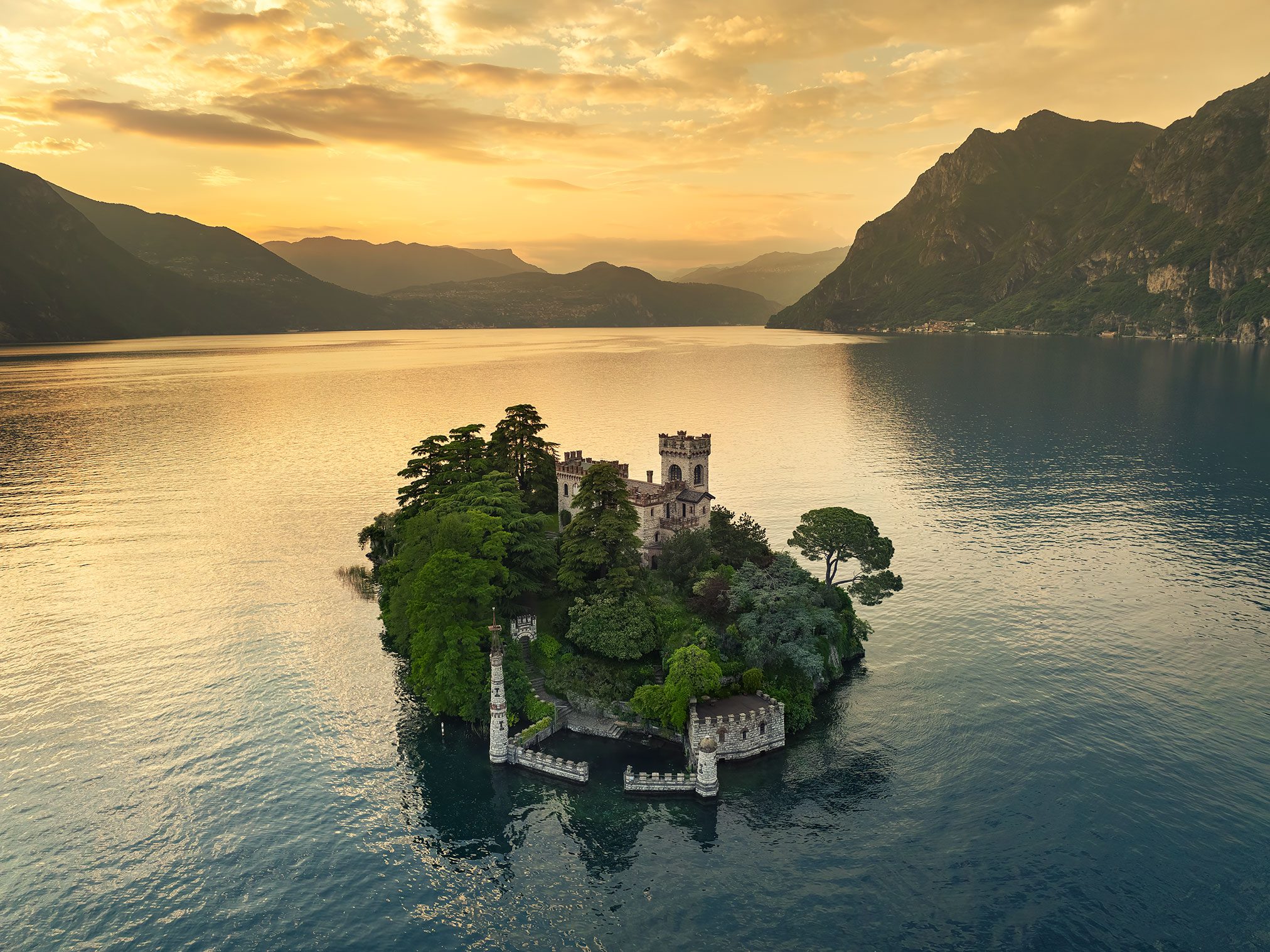 Aerial view of a tree covered castle island on a lake in Italy