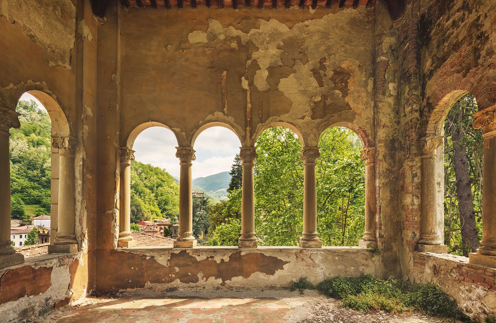 Vaulted loggia with a row of columns overlooking hills and rooftops, Italy