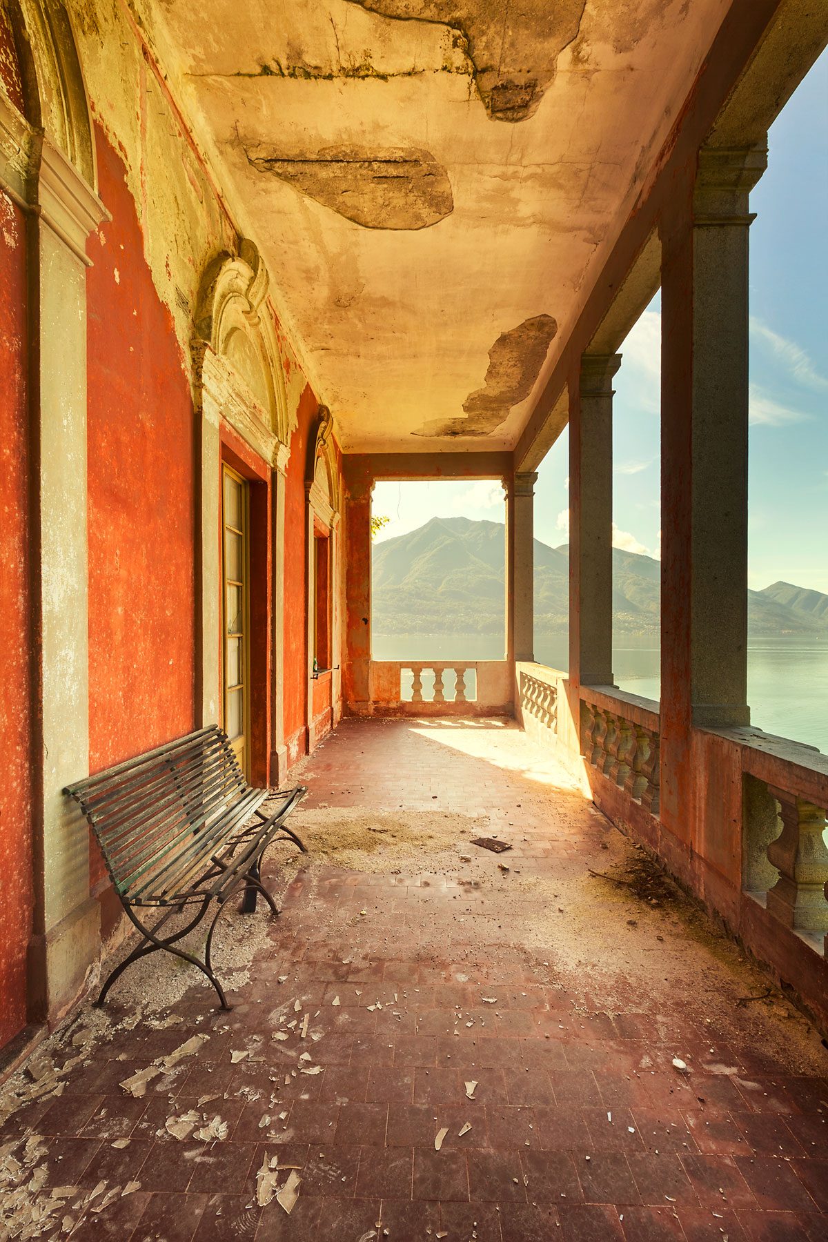 Covered terrace with a red wall and lake view in Italy