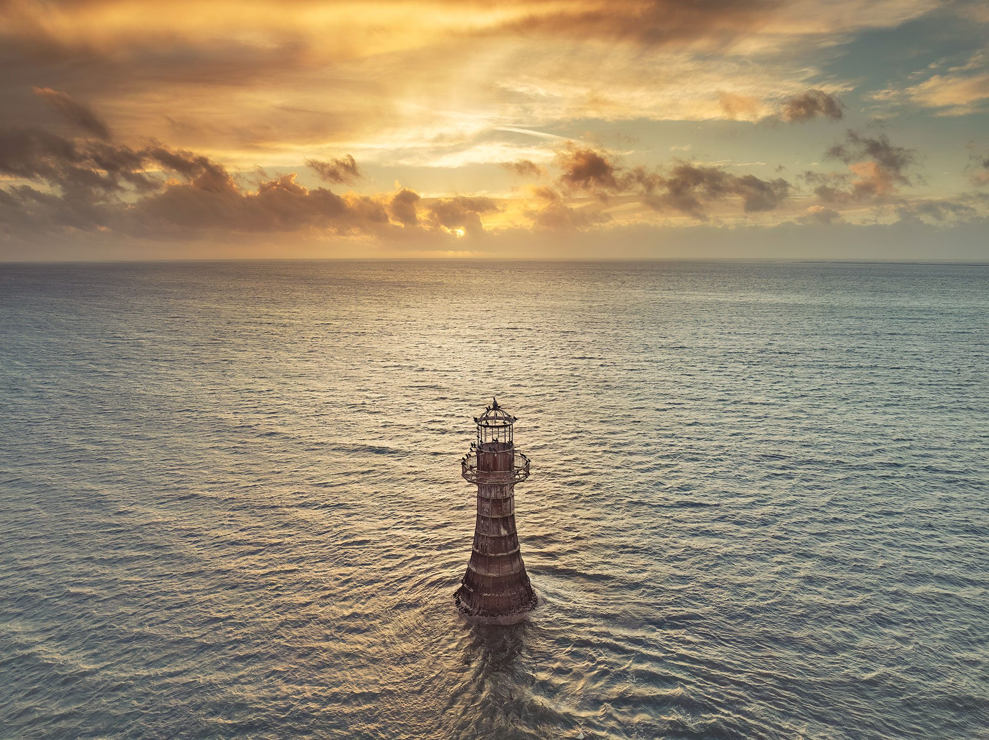 Cast iron lighthouse in the open sea at sunset, Wales