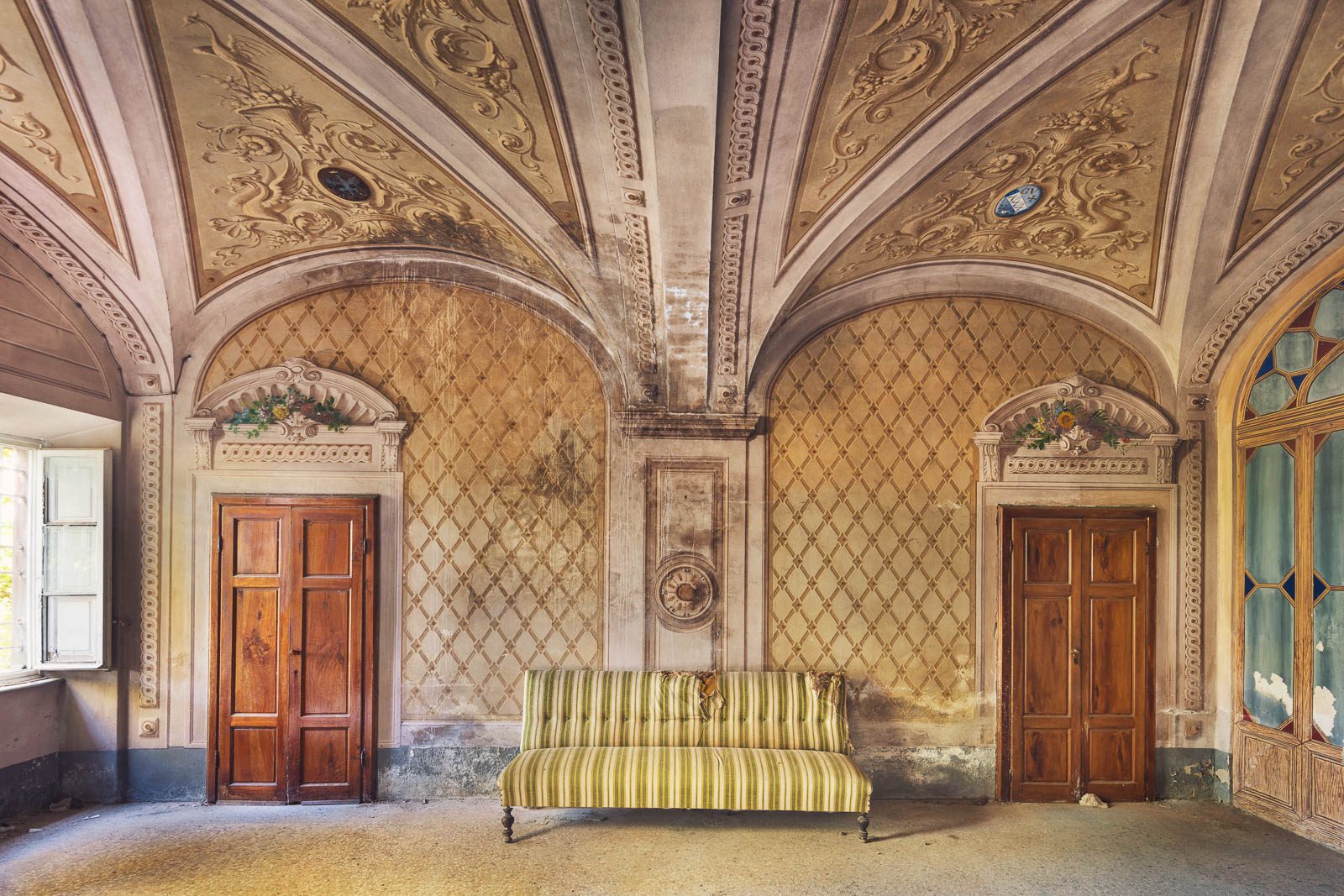 Gestreiftes Sofa unter gewölbter Stuckdecke in einer verlassenen Villa in der Toskana