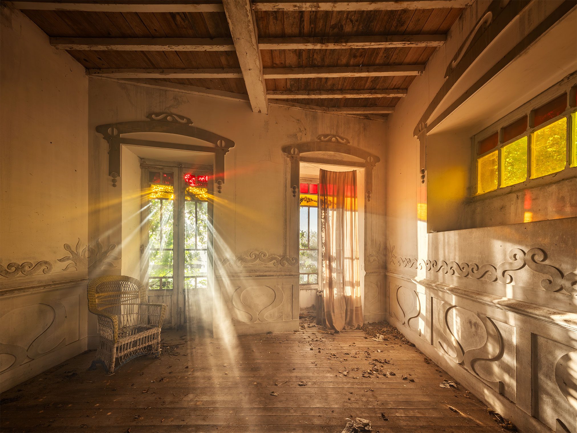 Abandoned room with shafts of light and a wicker chair in an Art Nouveau villa in Spain