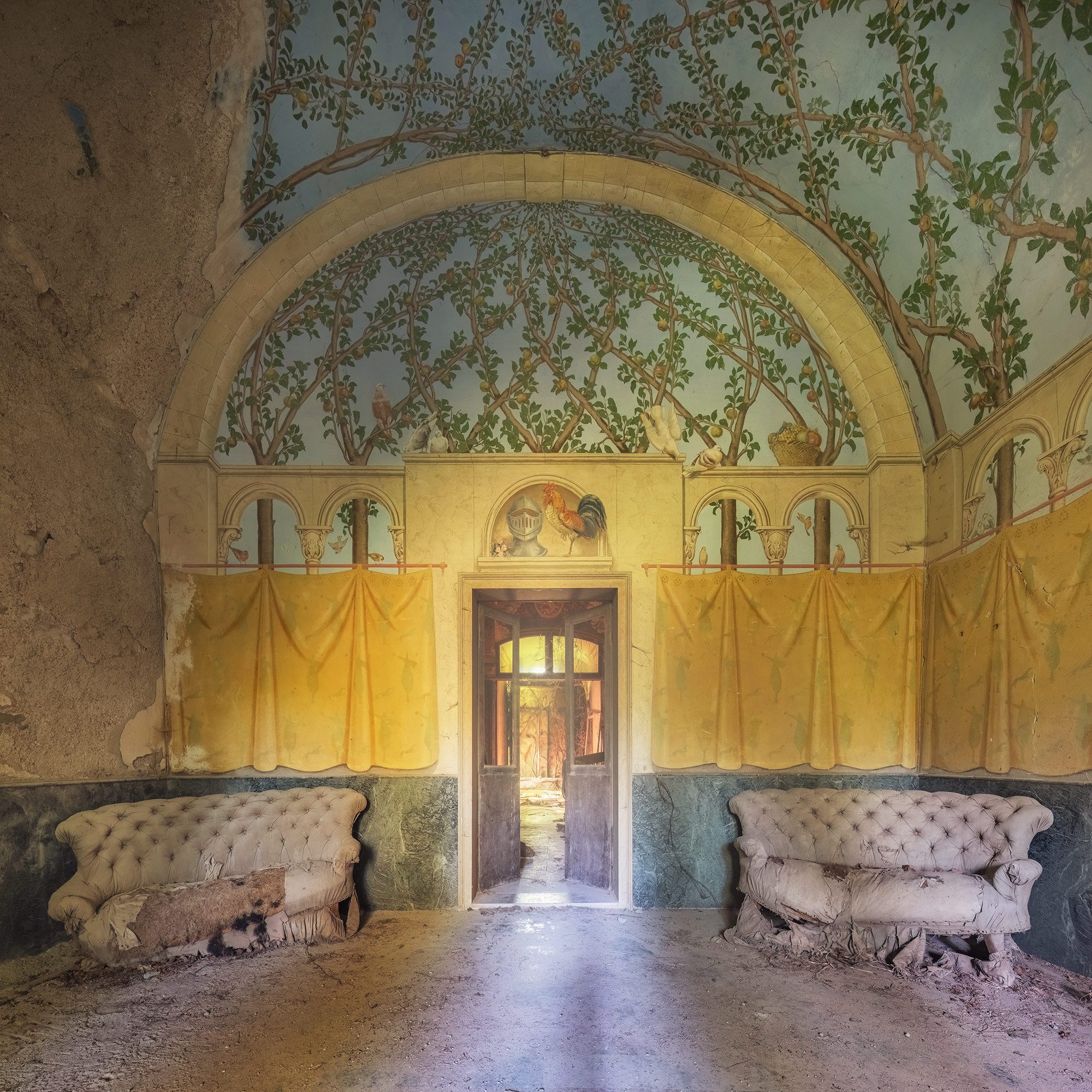 Sofas beneath a painted orange tree fresco in the hall of an old castello in Italy