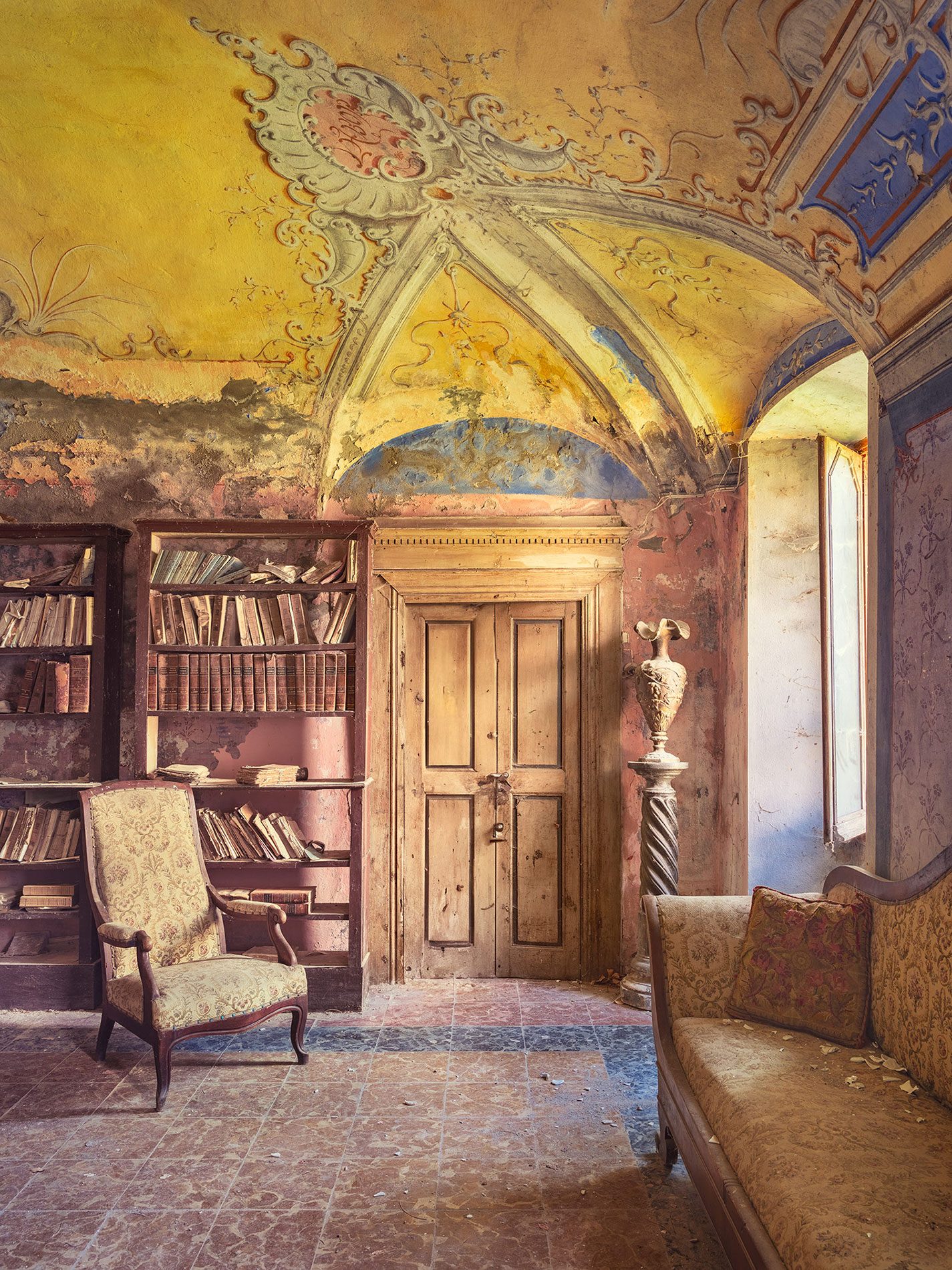 Armchair before a bookshelf in a forgotten villa in Italy