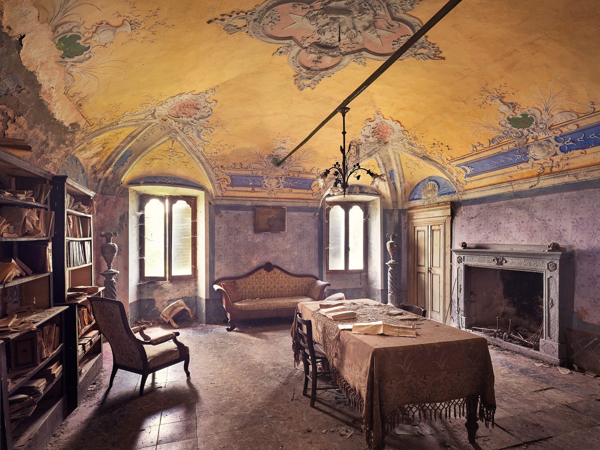 Parlour with bookshelf and fireplace in a forgotten villa in Italy