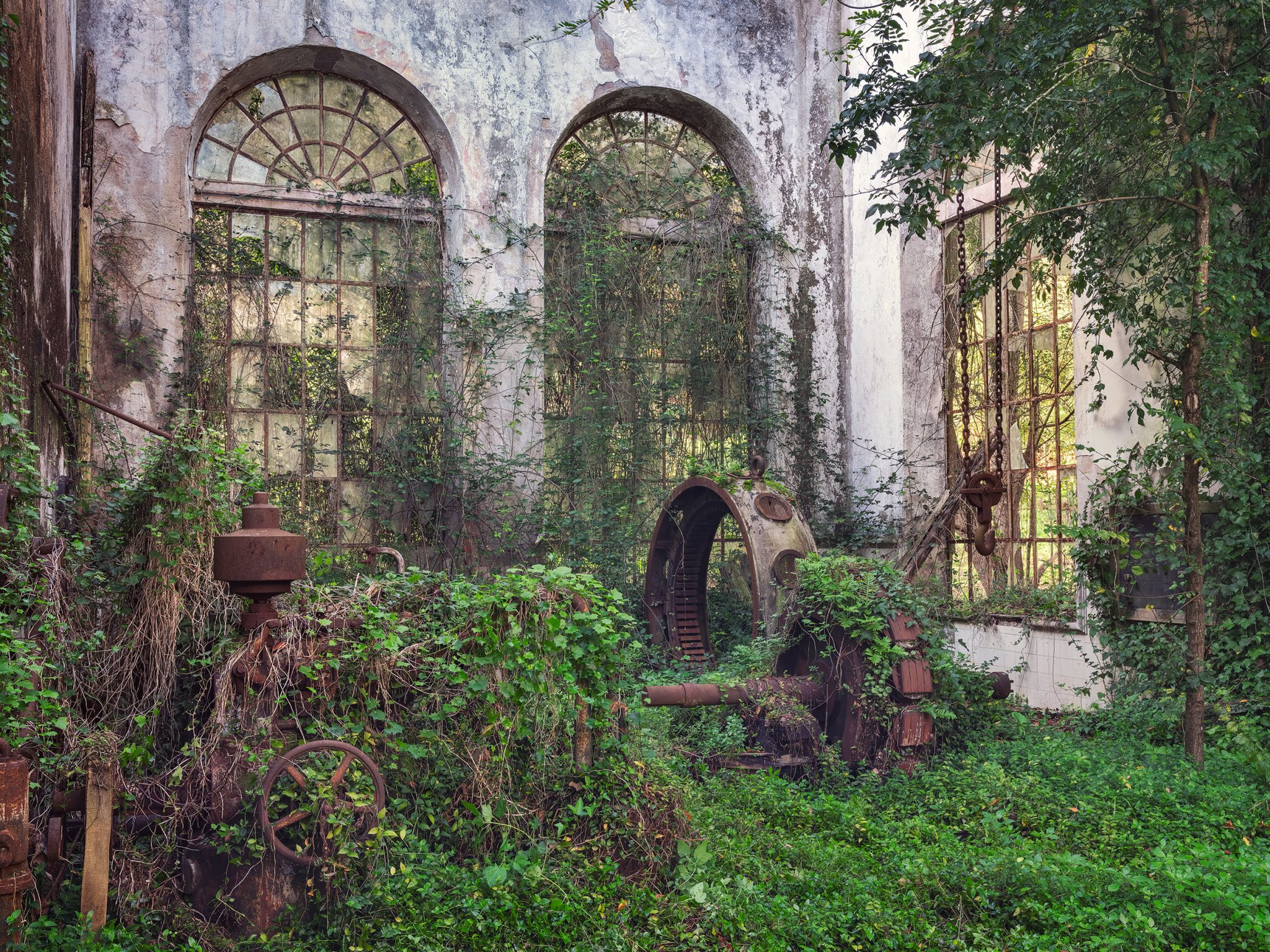 Ivy-covered turbine remains before two arched windows in a hydroelectric plant in Portugal