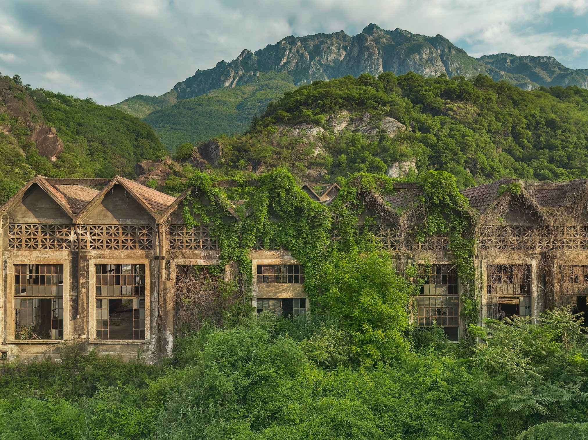Factory building with a sawtooth roof before a mountain range in Italy