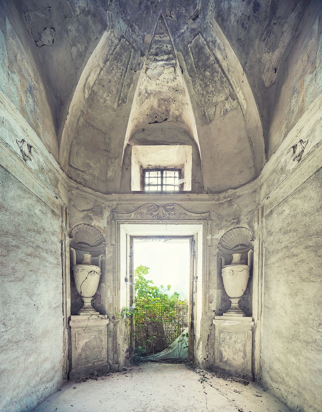 Symmetrical room with stone urns in shell niches in a forgotten villa in Piedmont, Italy