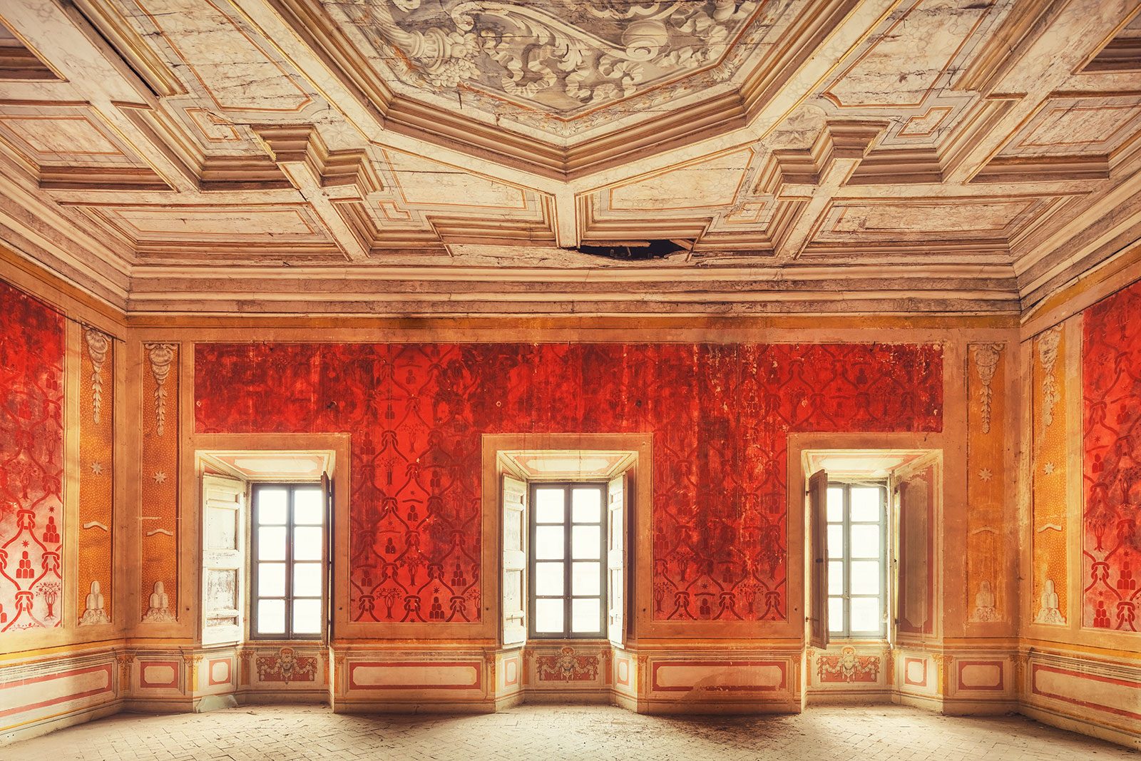 Saal mit rotem Damastmuster und geschnitzter Stuckdecke in einem verlassenen Palazzo in Umbrien, Italien