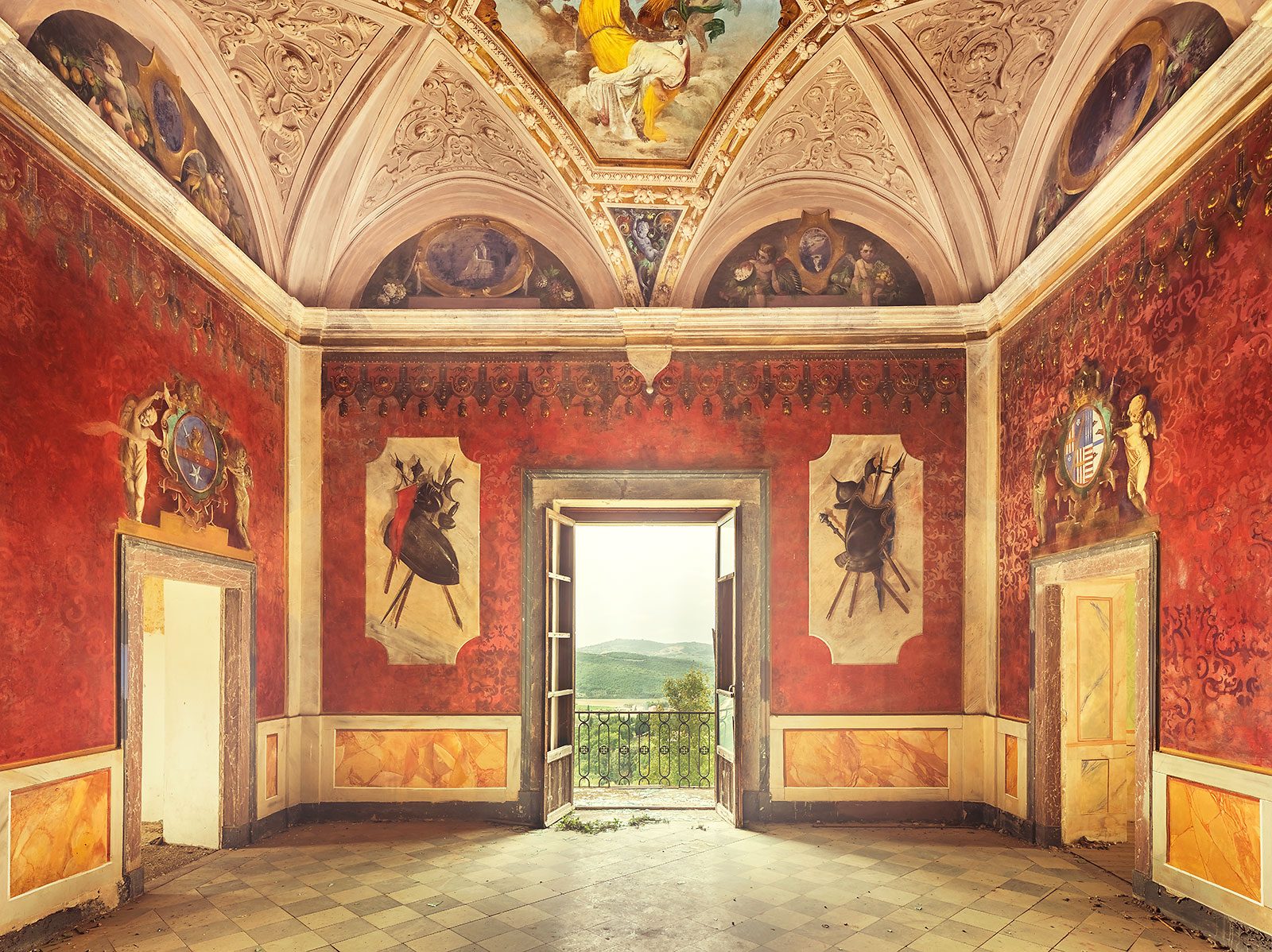 Saal mit roten Wappenfresken und offener Balkontür in einem verlassenen Kloster in der Toskana, Italien