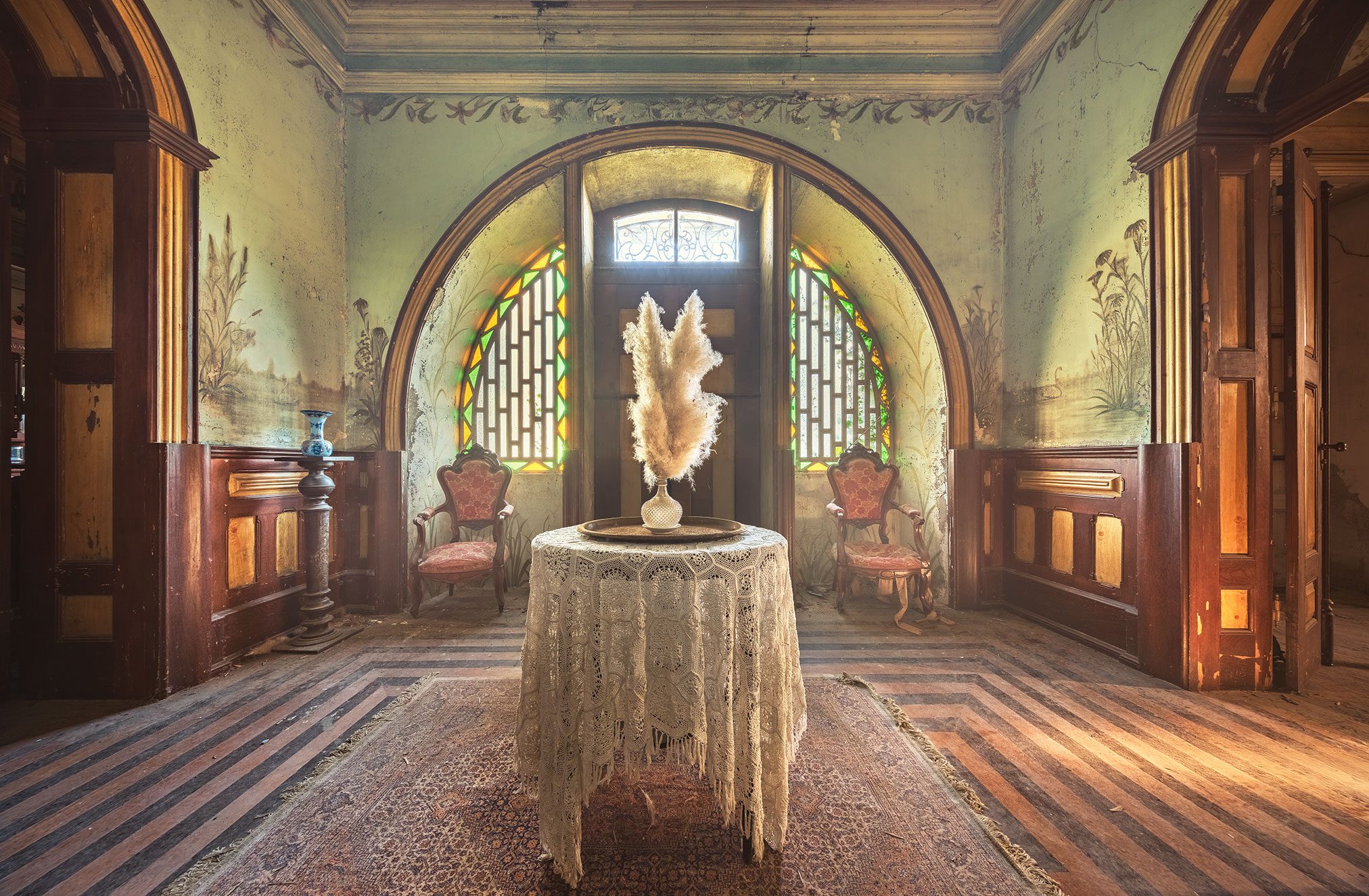 Salon mit gemalten Wandbildern und bunten Glasfenstern in einer verlassenen Jugendstil-Villa in Portugal